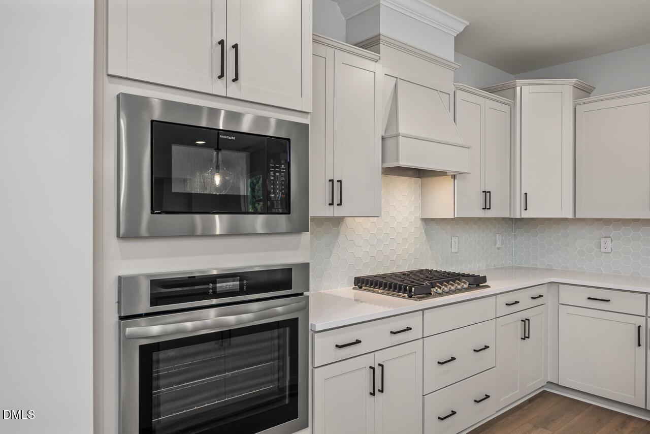 Modern kitchen with stainless steel oven, microwave, and gas cooktop in The Birch II E home at Sage on North Main.