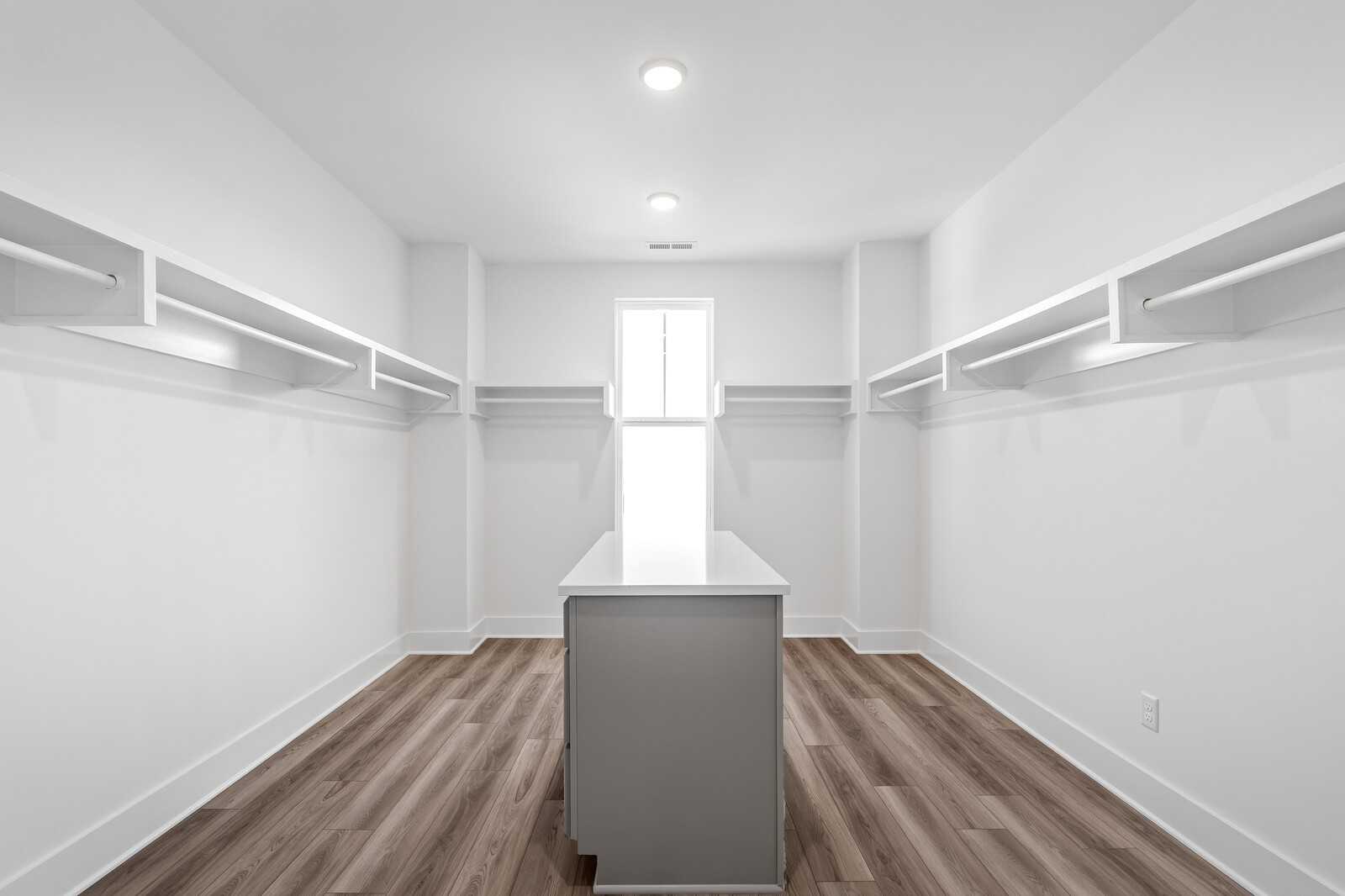 Spacious walk-in closet with white shelving, center island, and hardwood floors in Davidson Homes The Alston A, Murfreesboro