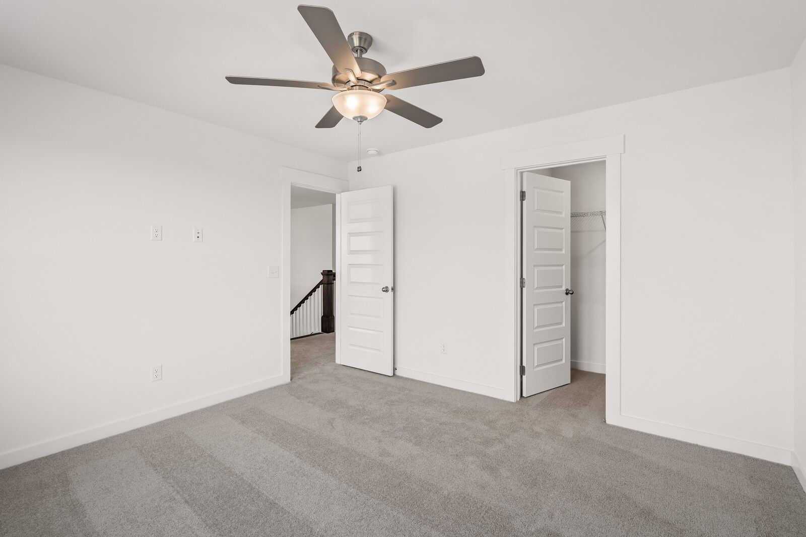 Spacious bedroom with ceiling fan, white doors, and gray carpet in Davidson Homes The Willow D, Mt. Juliet, TN