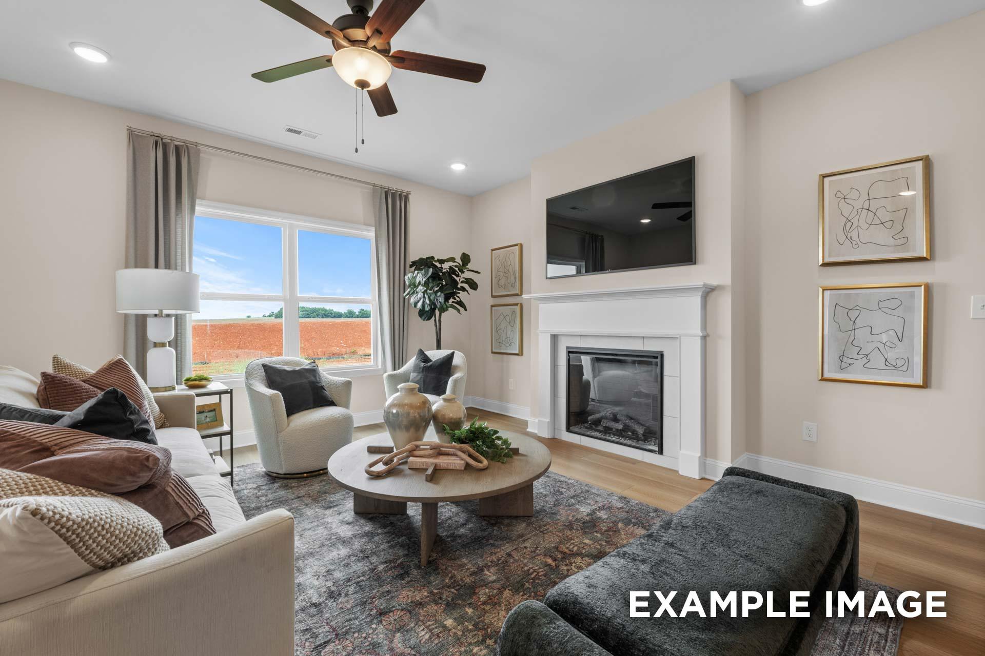 Spacious living room in The Laurel M featuring beige sofa, white fireplace, large windows, ceiling fan, and hardwood floors
