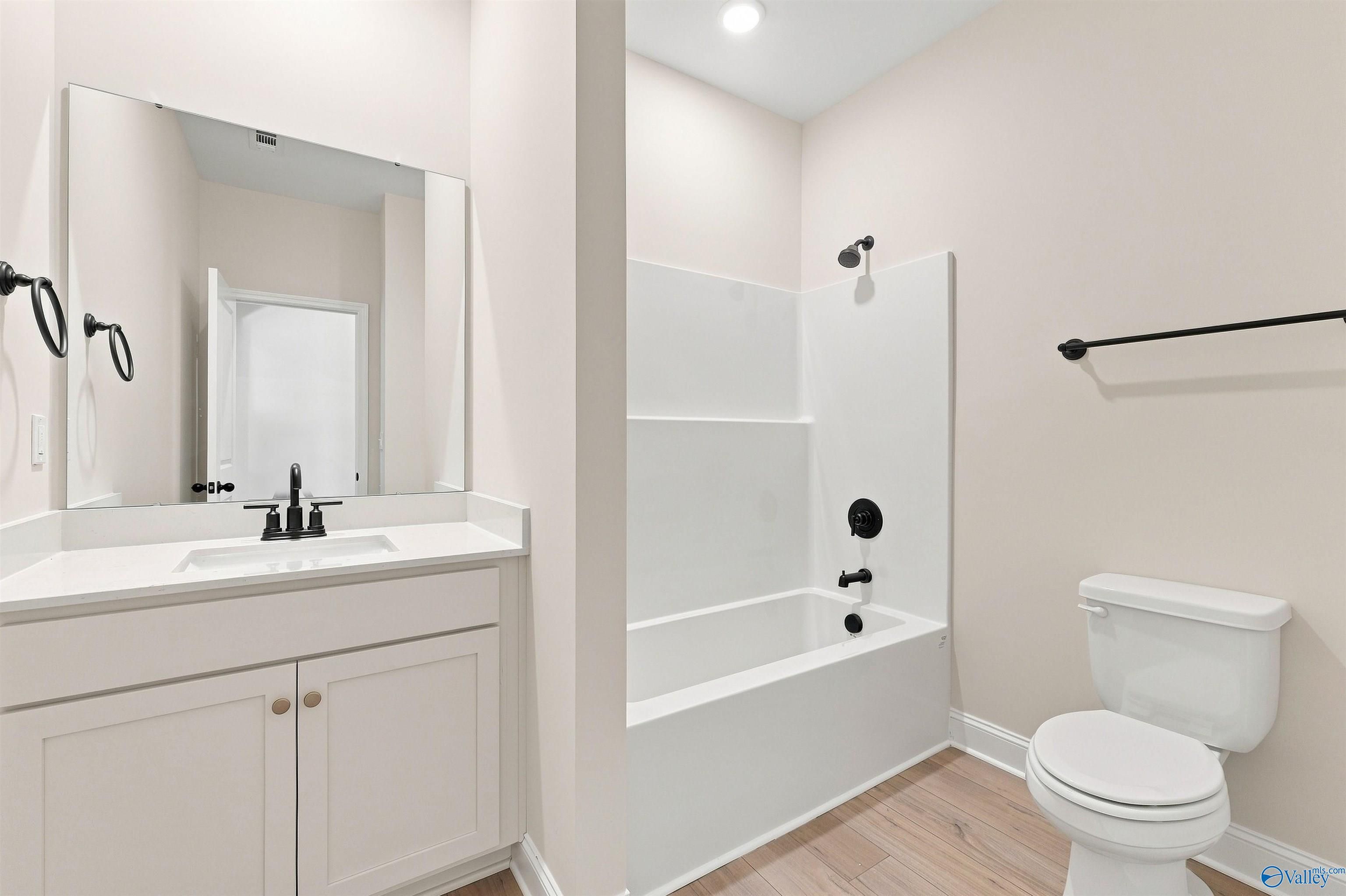 Modern full bathroom with white vanity, tub-shower combo, matte black fixtures, and wood-look flooring in Davidson Homes The Everett B plan