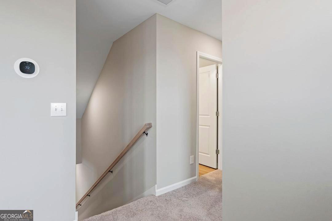 Upper level hallway with smart thermostat and staircase in The Stella floor plan by Davidson Homes in Ivy Glen, Perry, GA.