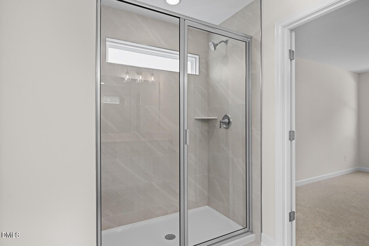Glass walk-in shower with tile surround in owner's bathroom of Davidson Homes The Willow B in Zebulon, North Carolina