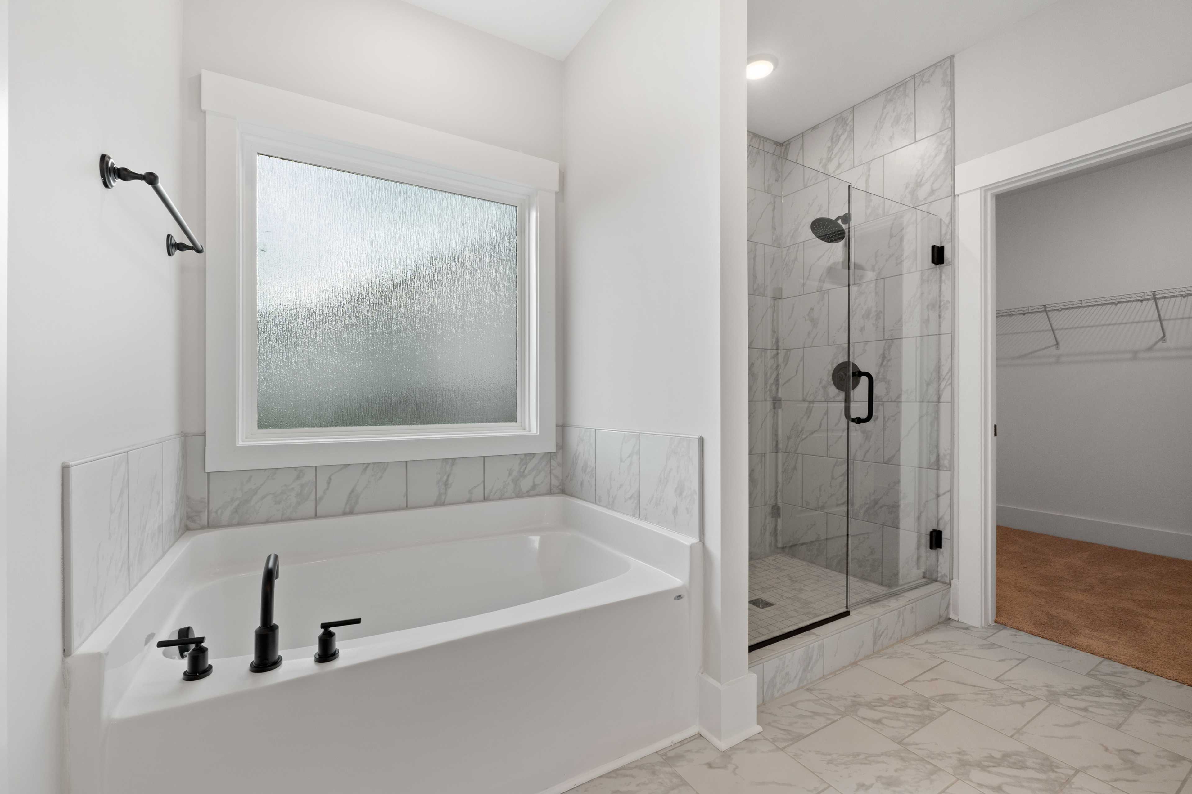 Spacious master bathroom at The Villas at Barnett's Crossing in Madison AL with freestanding tub, glass shower, and frosted window