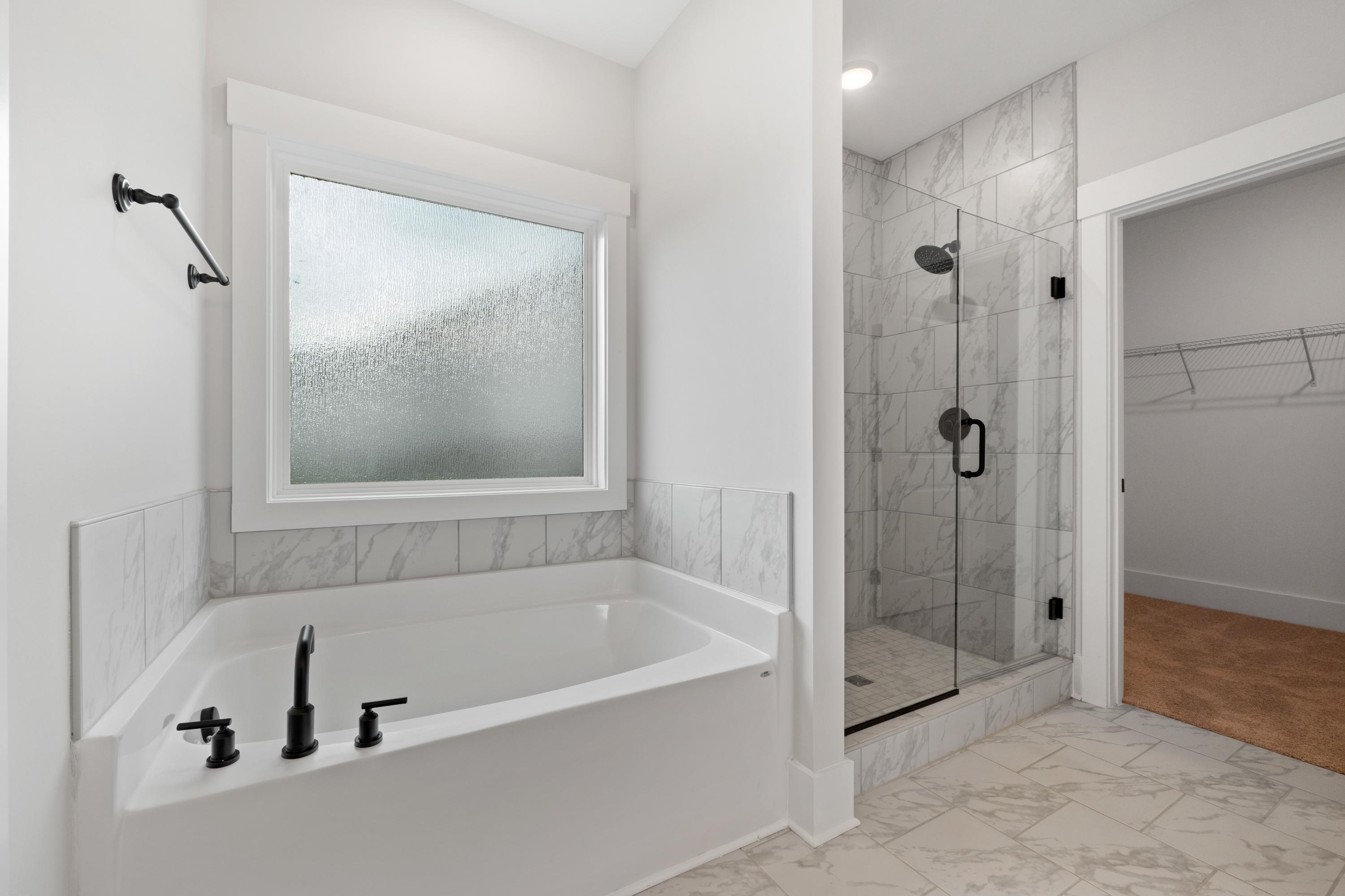 Spacious master bathroom at The Villas at Barnett's Crossing in Madison AL with freestanding tub, glass shower, and frosted window