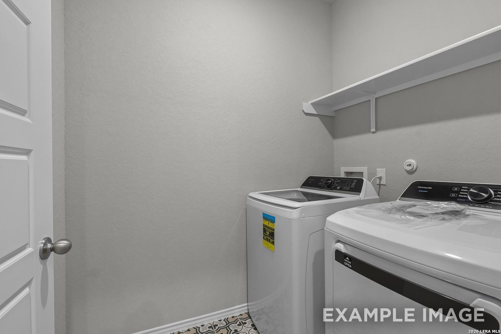 Modern laundry room with white washer, dryer, built-in shelves, and tiled floor in Davidson Homes The Colorado D, Agave, San Antonio