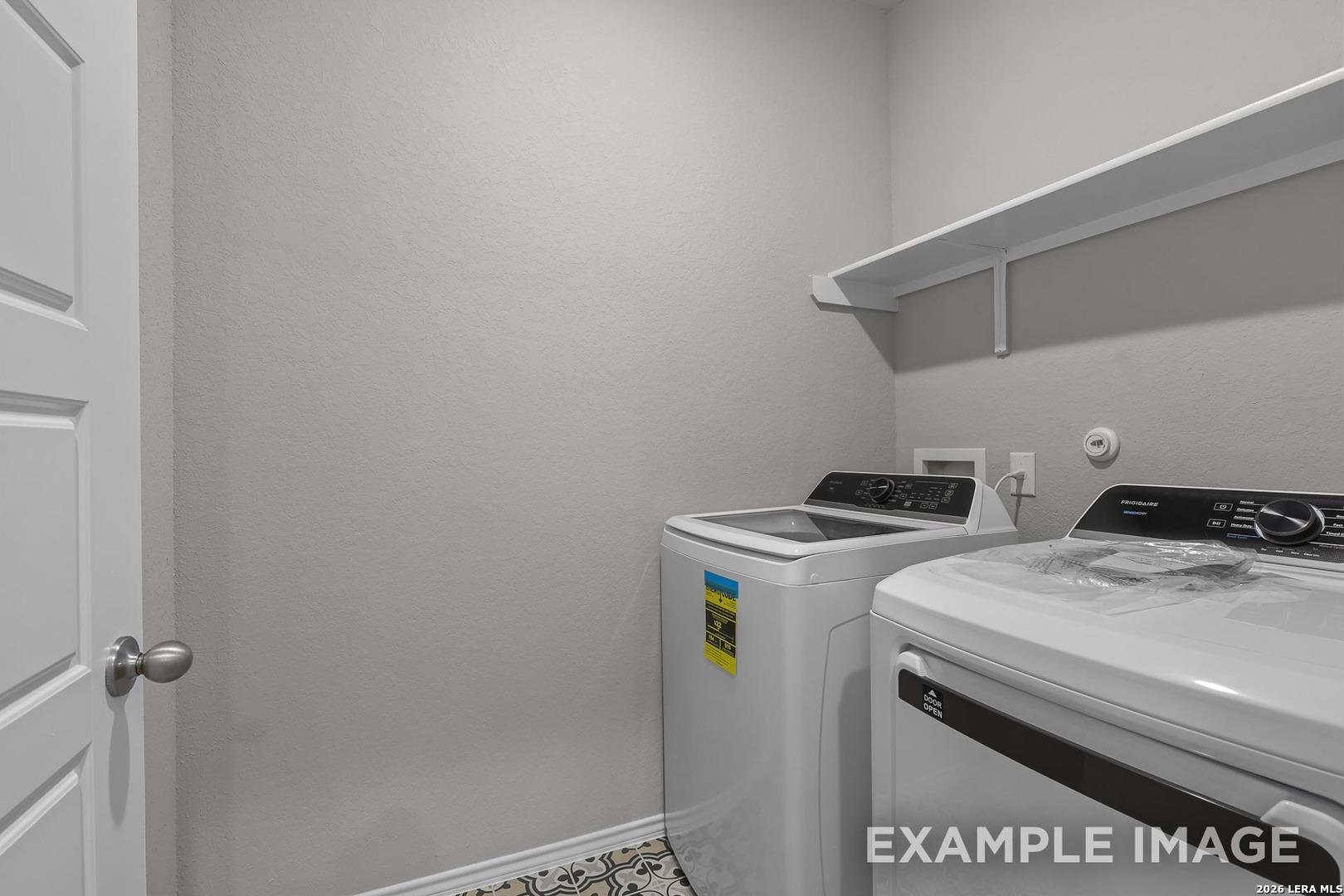 Modern laundry room with white washer, dryer, built-in shelves, and tiled floor in Davidson Homes The Colorado D, Agave, San Antonio