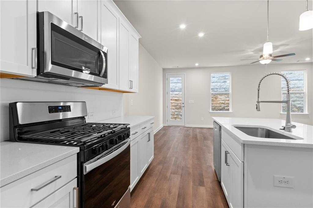 Modern white kitchen with stainless steel appliances, gas cooktop, and island sink in Davidson Homes The Marion B, Kennesaw, Georgia