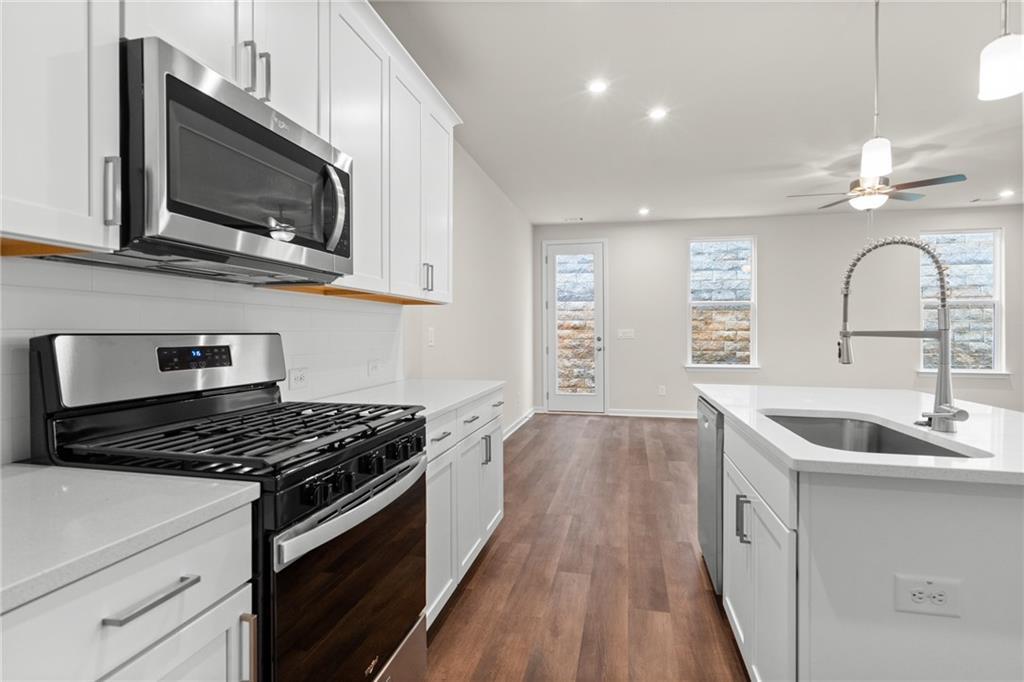 Modern white kitchen with stainless steel appliances, gas cooktop, and island sink in Davidson Homes The Marion B, Kennesaw, Georgia