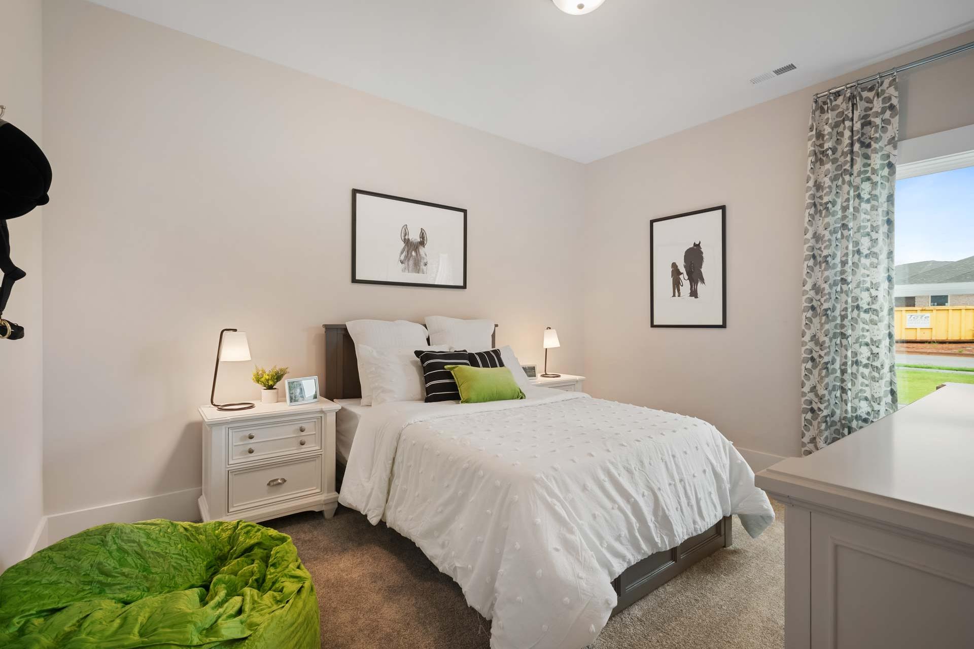 Cozy bedroom at Durham Farms in Harvest Alabama with white bed green bean bag modern artwork and natural light
