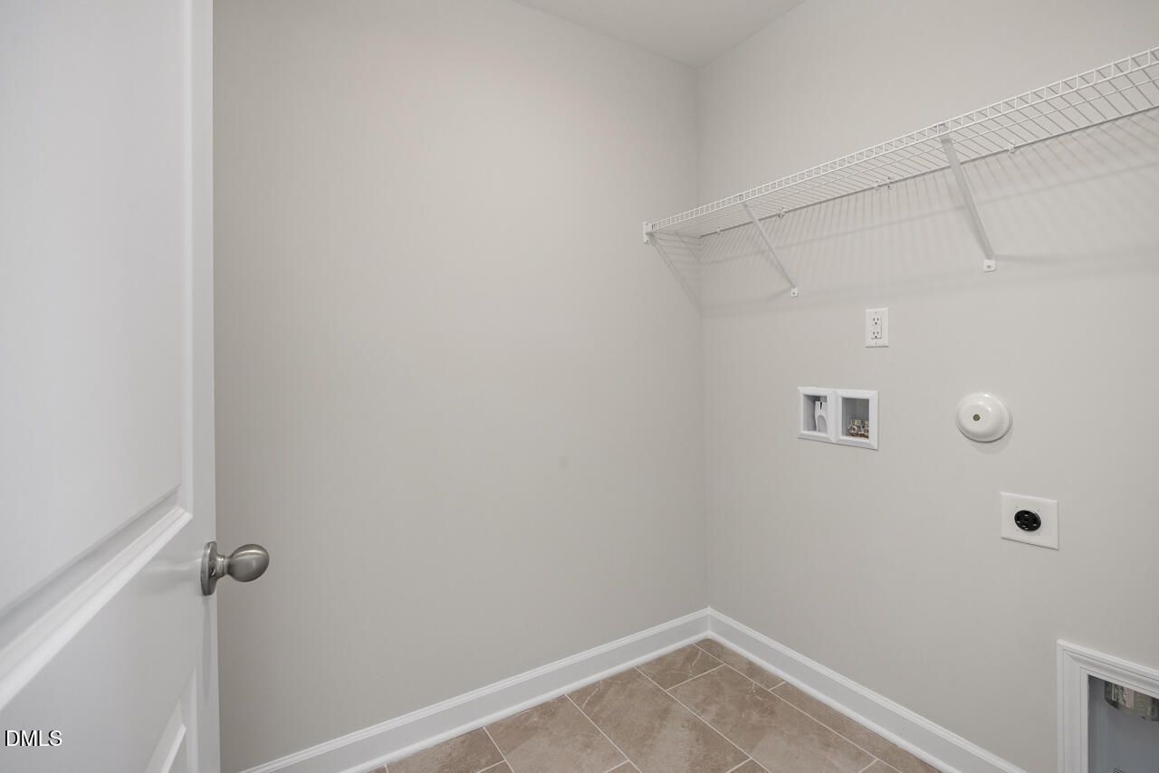Laundry room with wire shelving and tile flooring in The Adalynn A floor plan at Gregory Village, Lillington, NC.