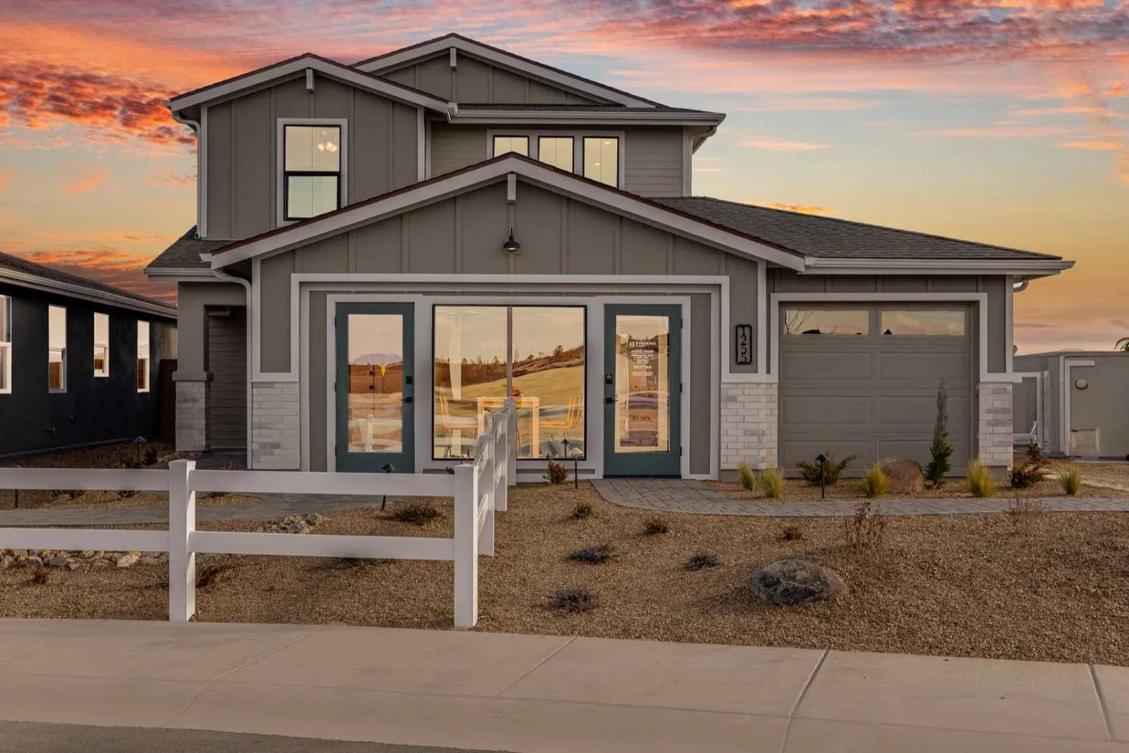 Modern two-story gray home exterior at South Ranch Southern Collection in Prescott AZ with large windows, garage, and desert yard at sunset