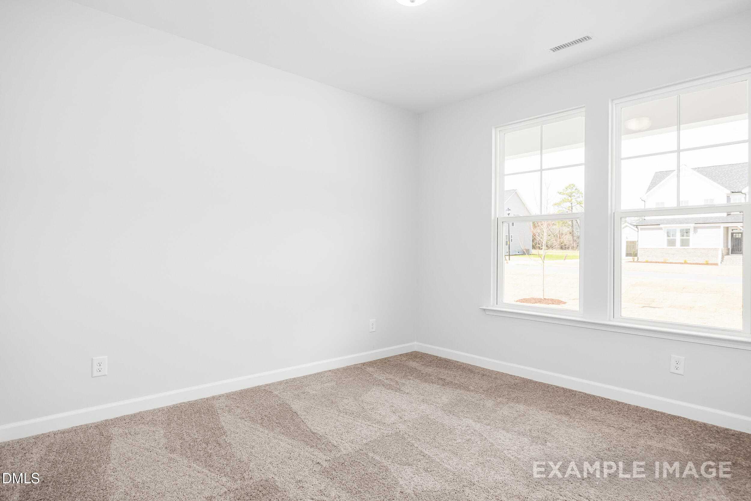 Bright secondary bedroom with beige carpet, white walls, and large windows overlooking yard in The Franklin C, Lillington, NC