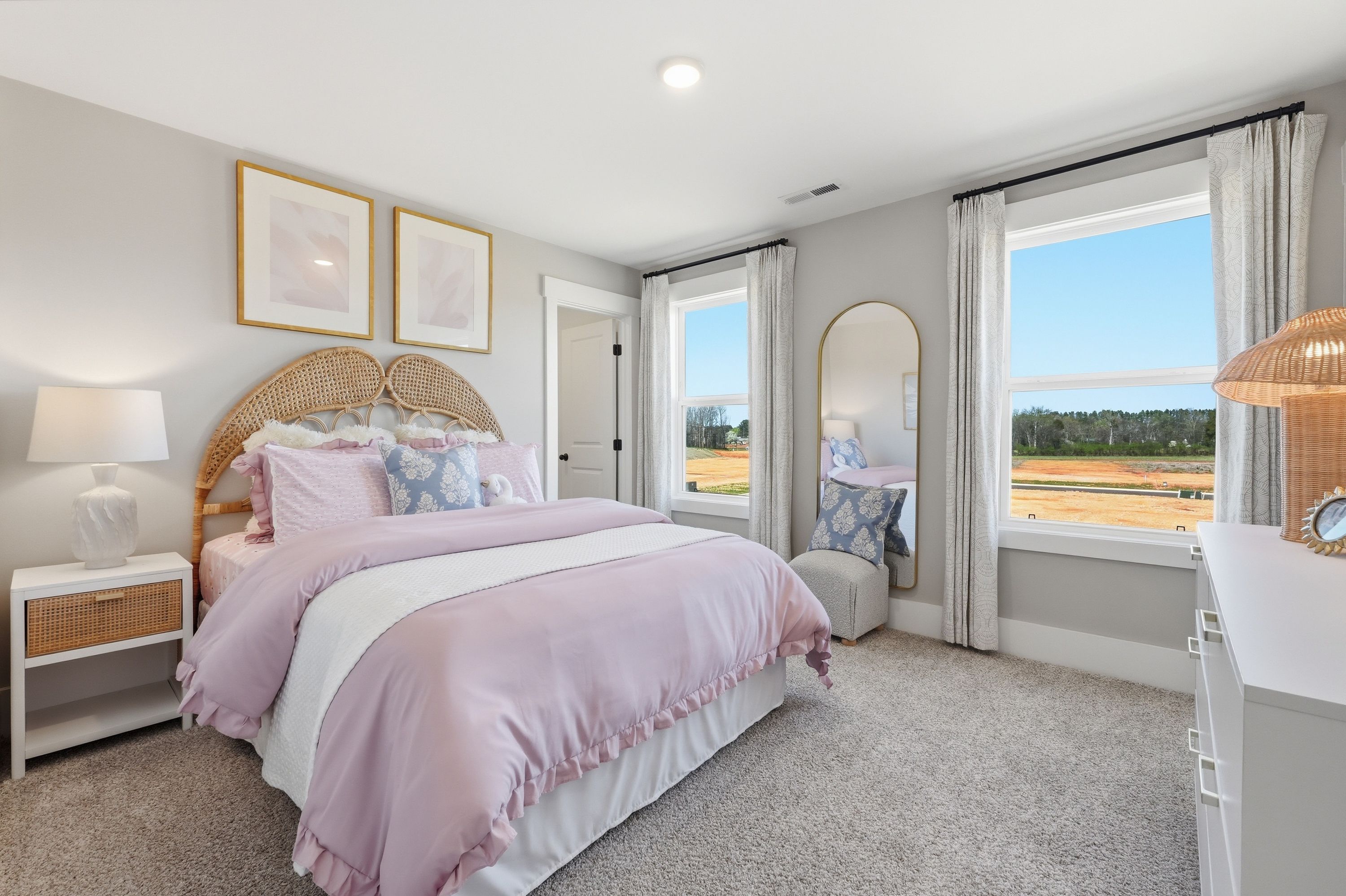 Spacious bedroom in Berry Cove, New Market Alabama with rattan headboard, pink bedding, large windows overlooking fields, and modern decor