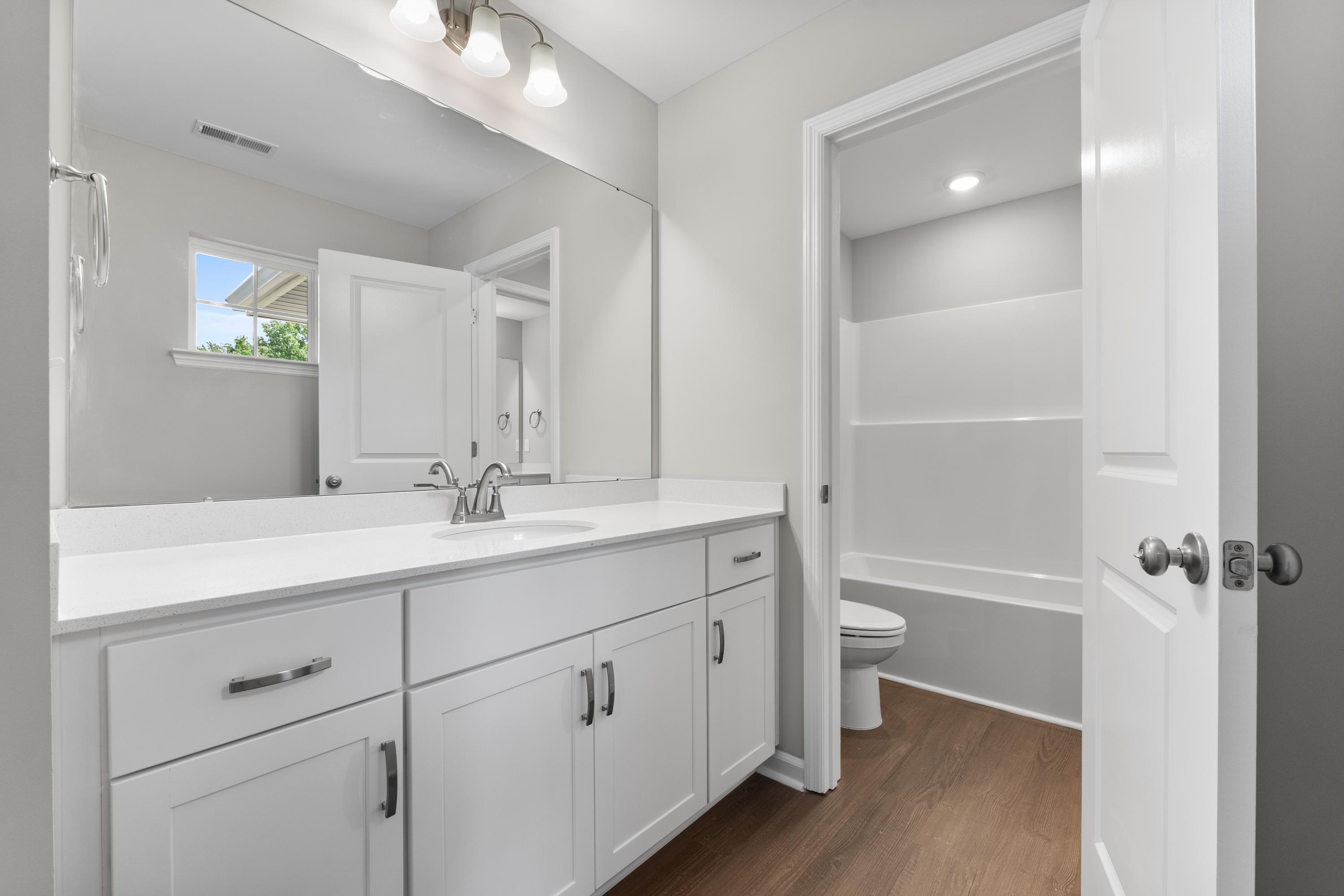 Spacious master bathroom in The Avalon D featuring white double vanity, soaking tub, and neutral tones