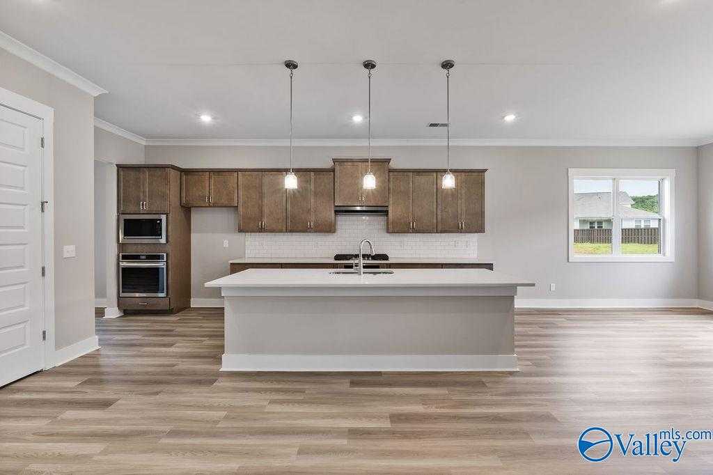 Modern kitchen with espresso cabinets, white quartz island, stainless appliances in Evermore Homes The Oxford, Owens Cross Roads