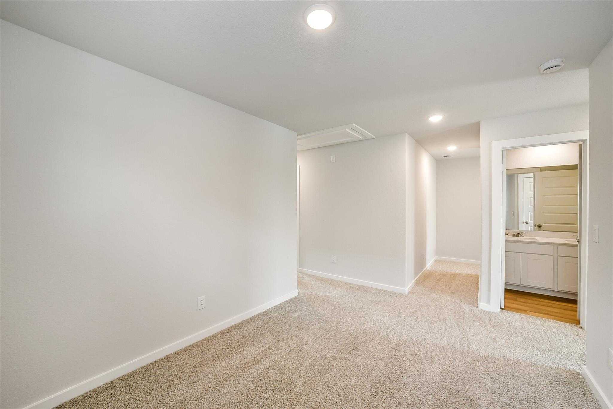 Spacious upstairs hallway with beige carpet, white walls, and adjacent bathroom vanity in Davidson Homes The Trinity F, Magnolia, Texas