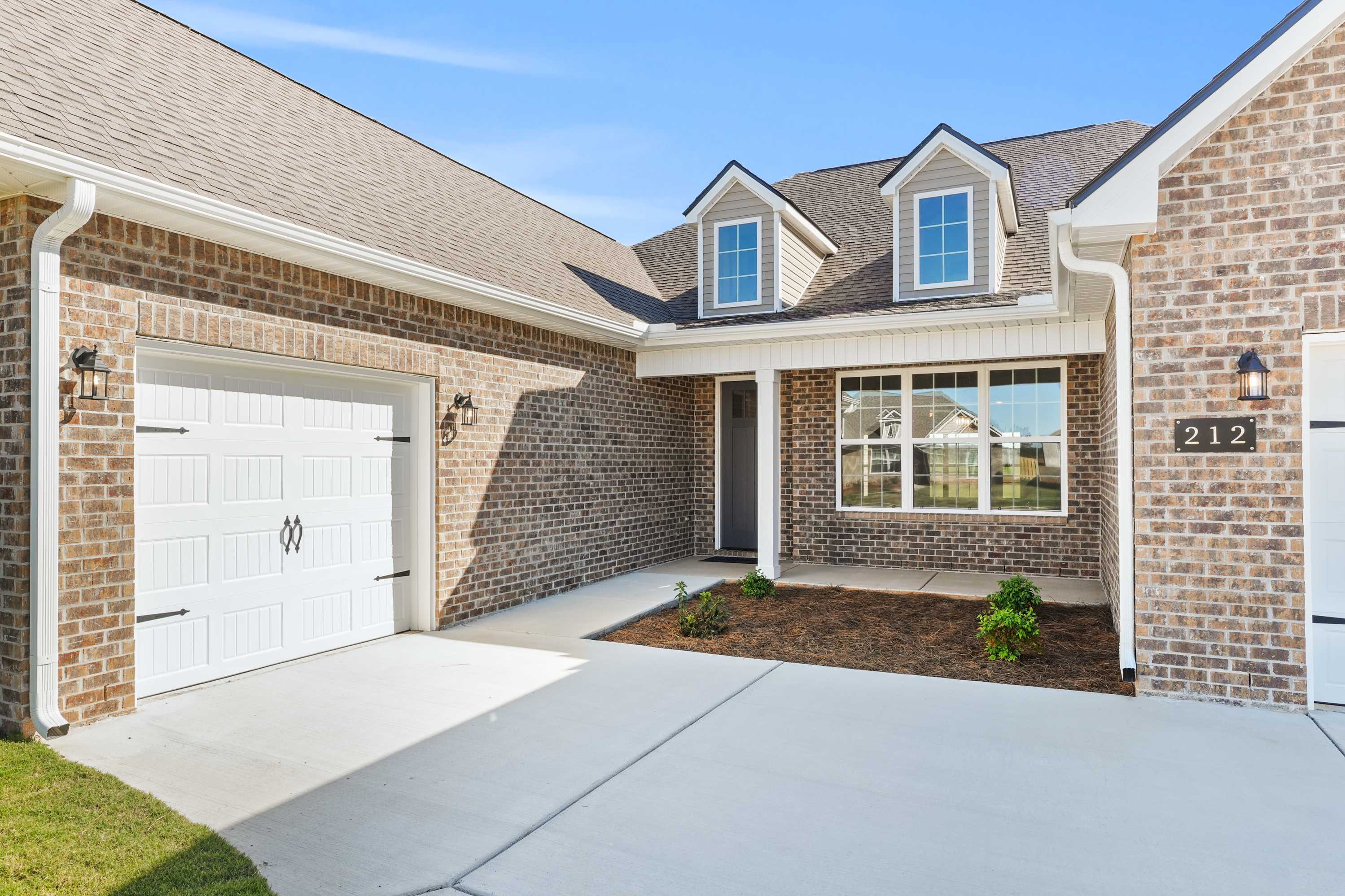 The Valencia 1-story home exterior: brick facade, 3-car garage, dormer windows, and landscaped driveway in Meridianville, AL