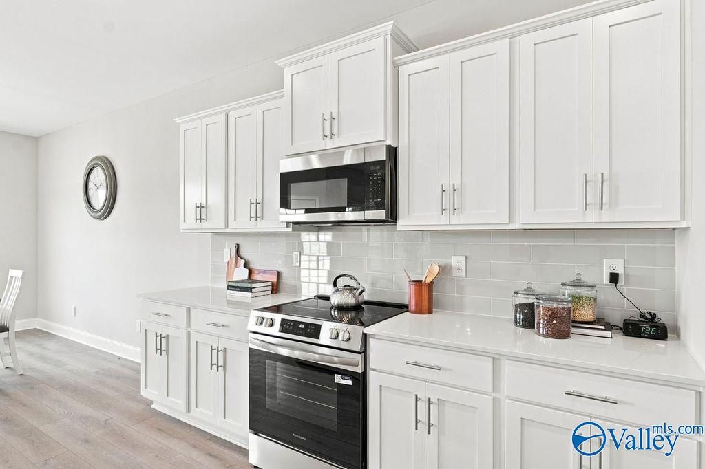 Modern white kitchen with stainless appliances and subway tile backsplash in Davidson Homes The Harrison, Hartselle, Alabama