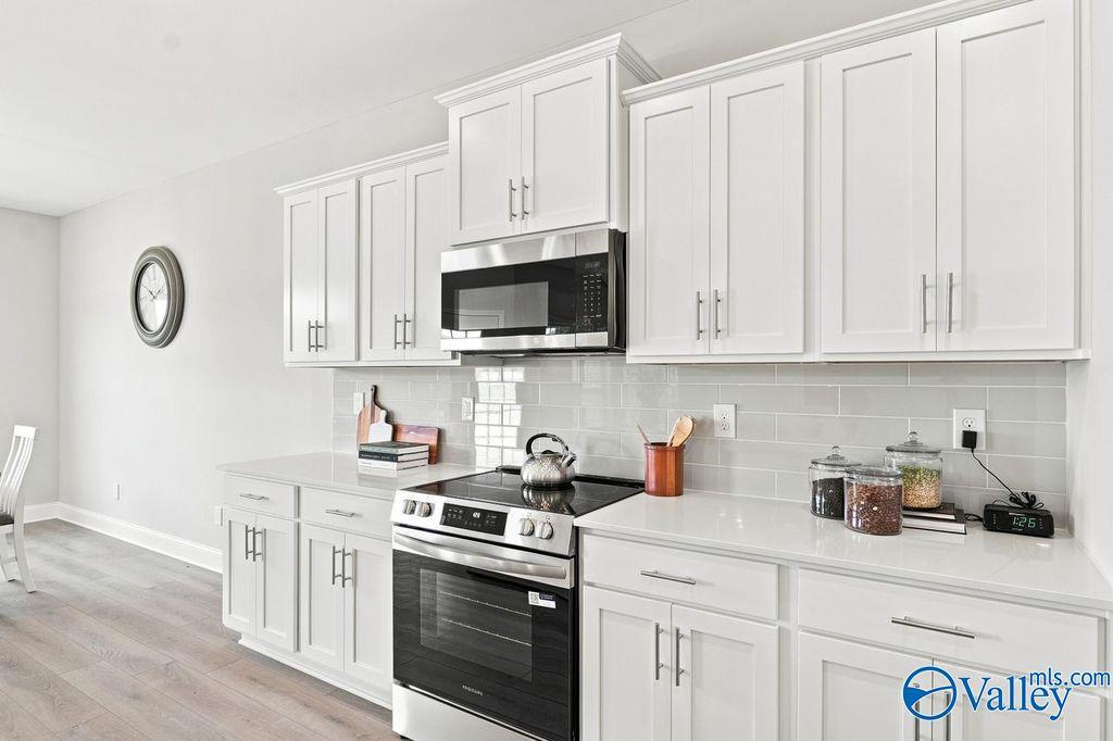 Modern white kitchen with stainless appliances and subway tile backsplash in Davidson Homes The Harrison, Hartselle, Alabama