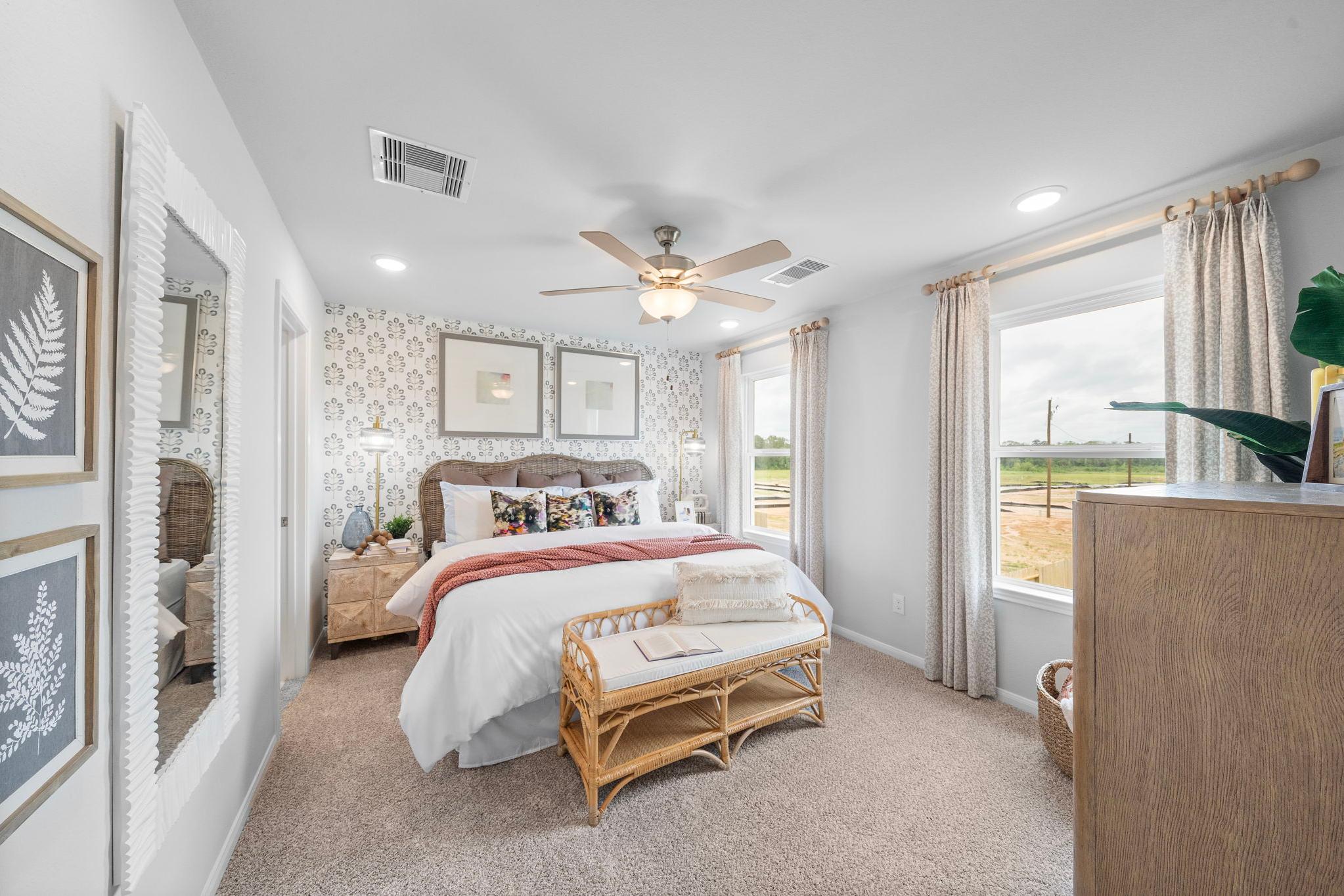 Spacious primary bedroom at Hill & Dale Ranch in Splendora Texas with king bed, ceiling fan, rattan bench, and large windows