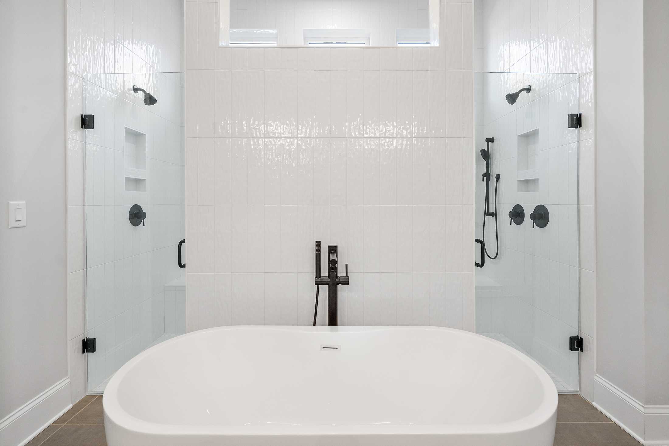 Luxurious master bathroom in The Seaside with freestanding oval tub, dual glass showers, white subway tile