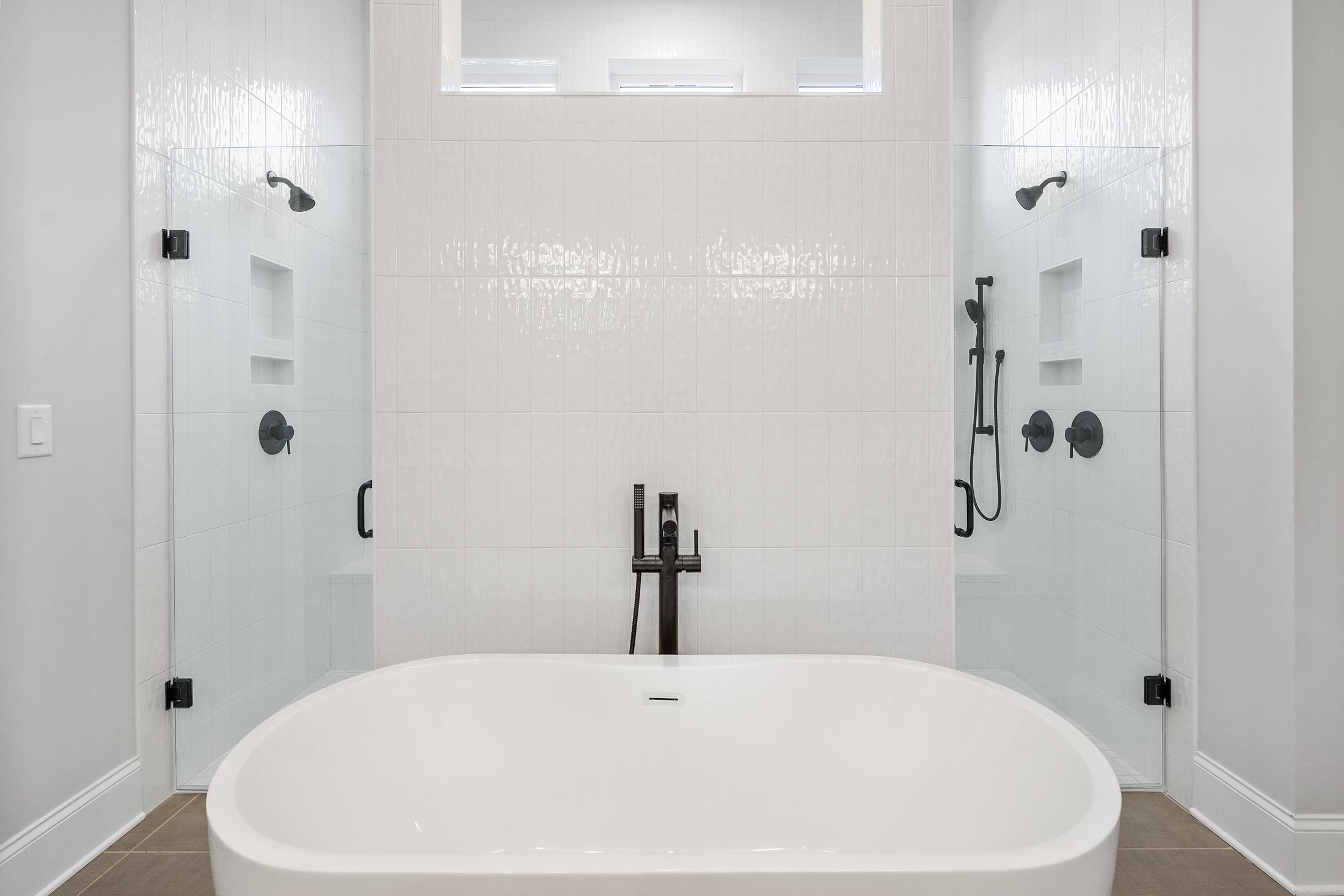 Luxurious master bathroom in The Seaside with freestanding oval tub, dual glass showers, white subway tile