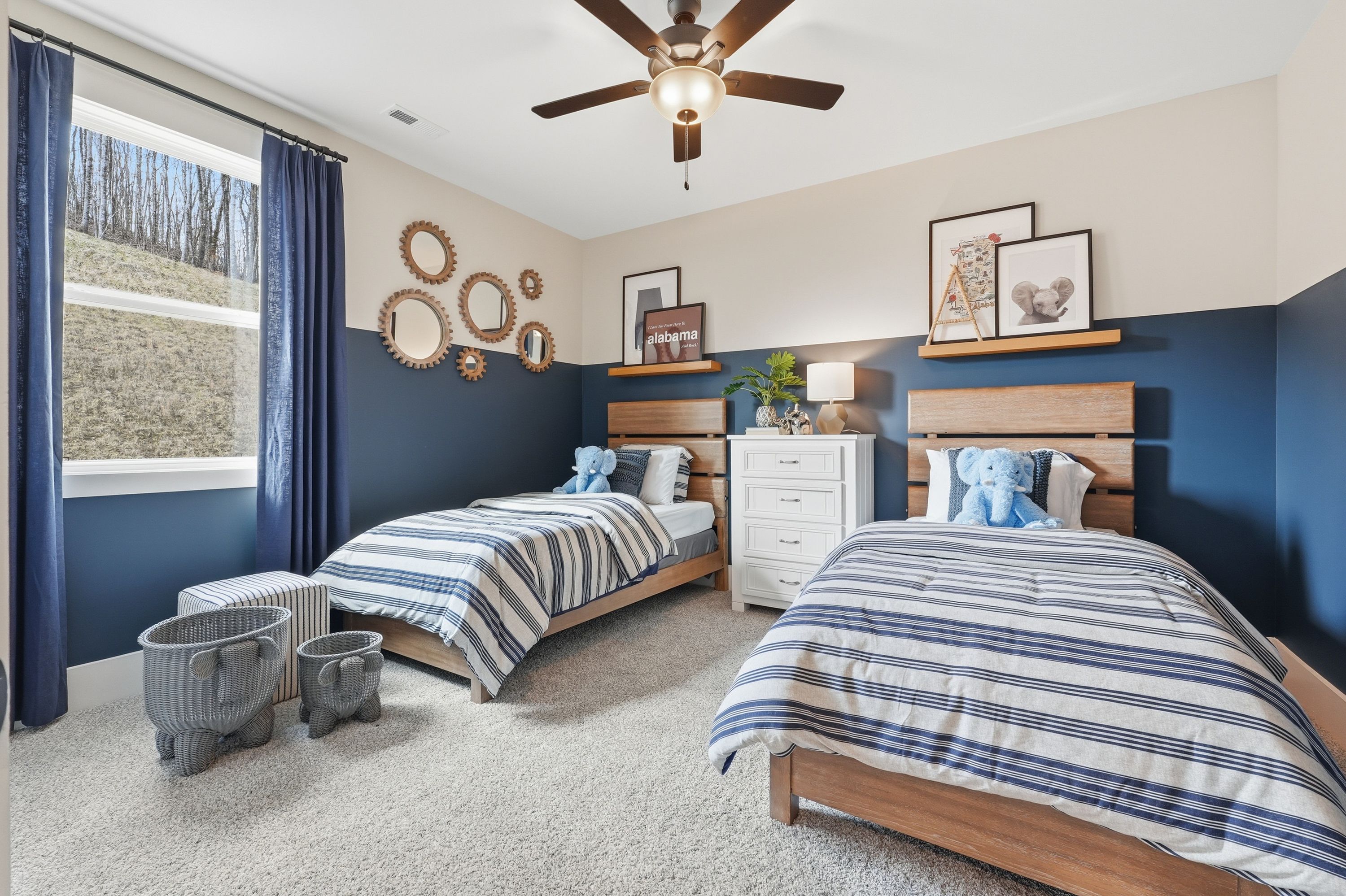 Cozy kids bedroom at Noble Ridge in Cullman Alabama with twin beds navy accent wall wooden dresser and elephant decor
