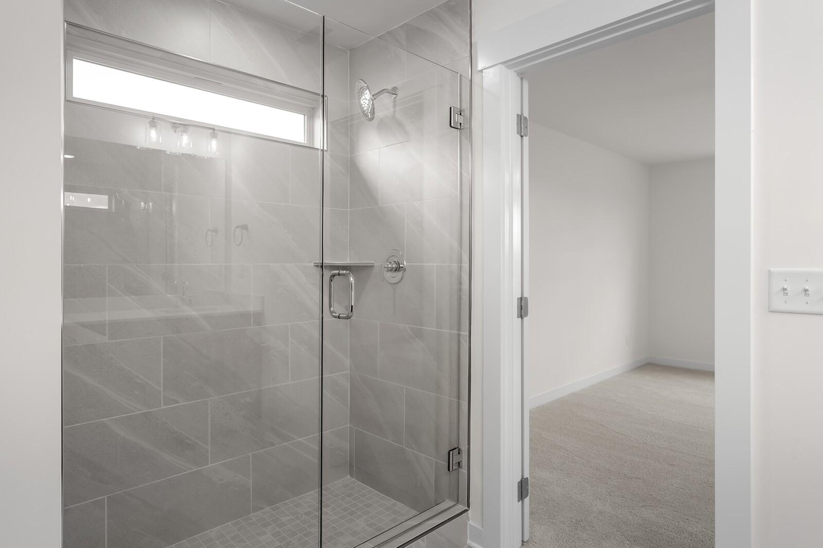 Modern frameless glass walk-in shower with gray subway tiles and rainfall head in master bathroom, Davidson Homes The Willow C, Gallatin TN