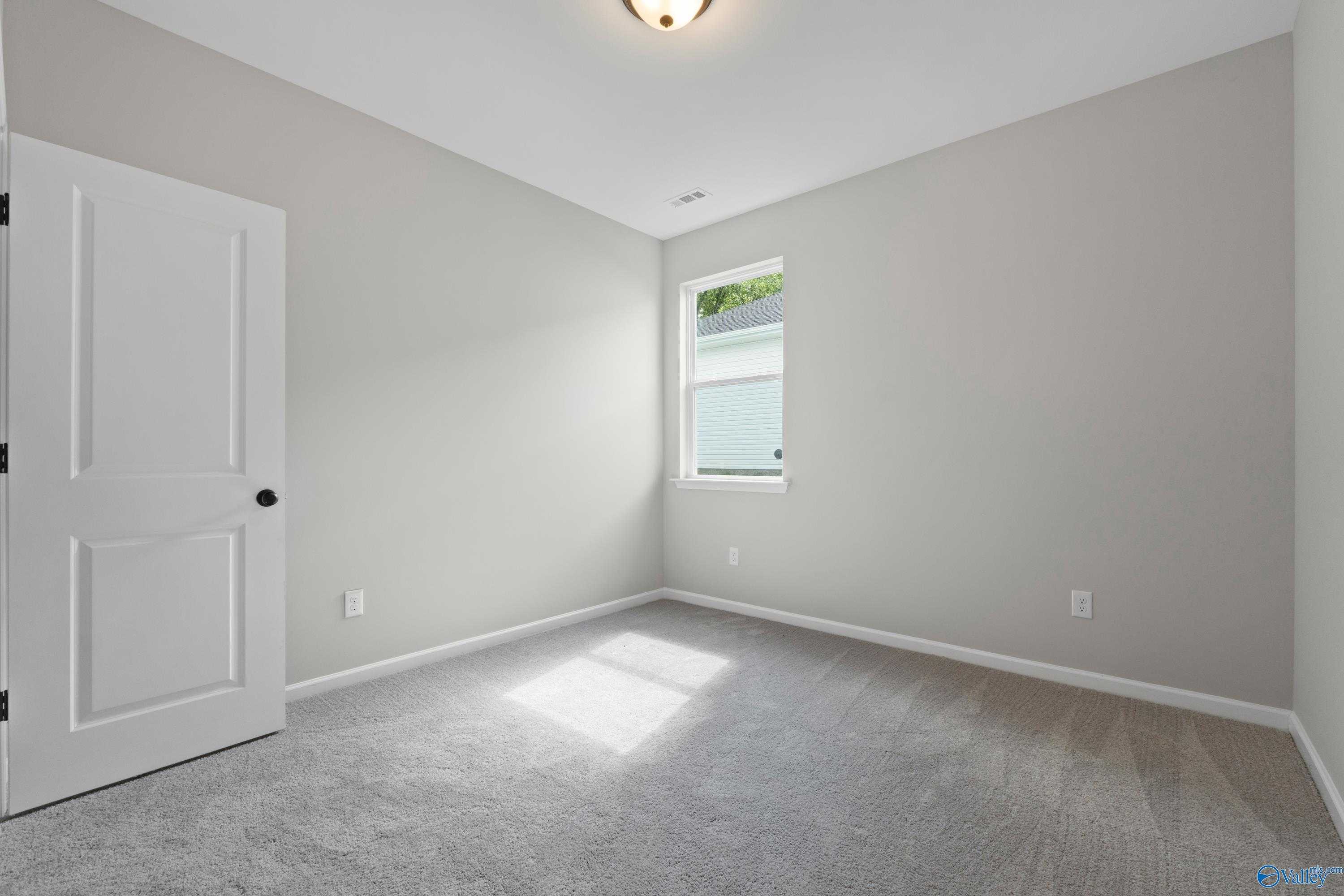 Bright secondary bedroom with light gray walls, plush carpet, and sunlit window in Davidson Homes The Phoenix, Fayetteville, TN
