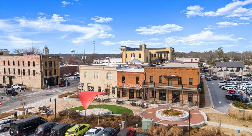 Aerial view of charming downtown Winder, Georgia, with historic brick buildings, red sculpture in landscaped roundabout, shops, and parked cars near Cedar Farms