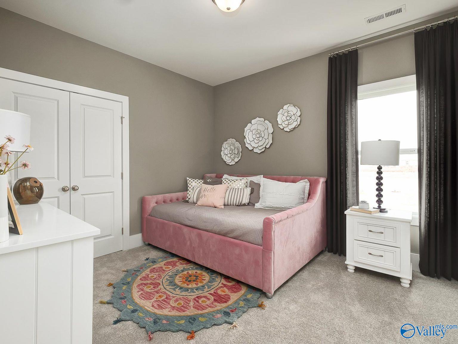 Cozy secondary bedroom with pink velvet daybed, gray walls, floral wall art, and patterned rug in Davidson Homes The Everett, Toney, AL
