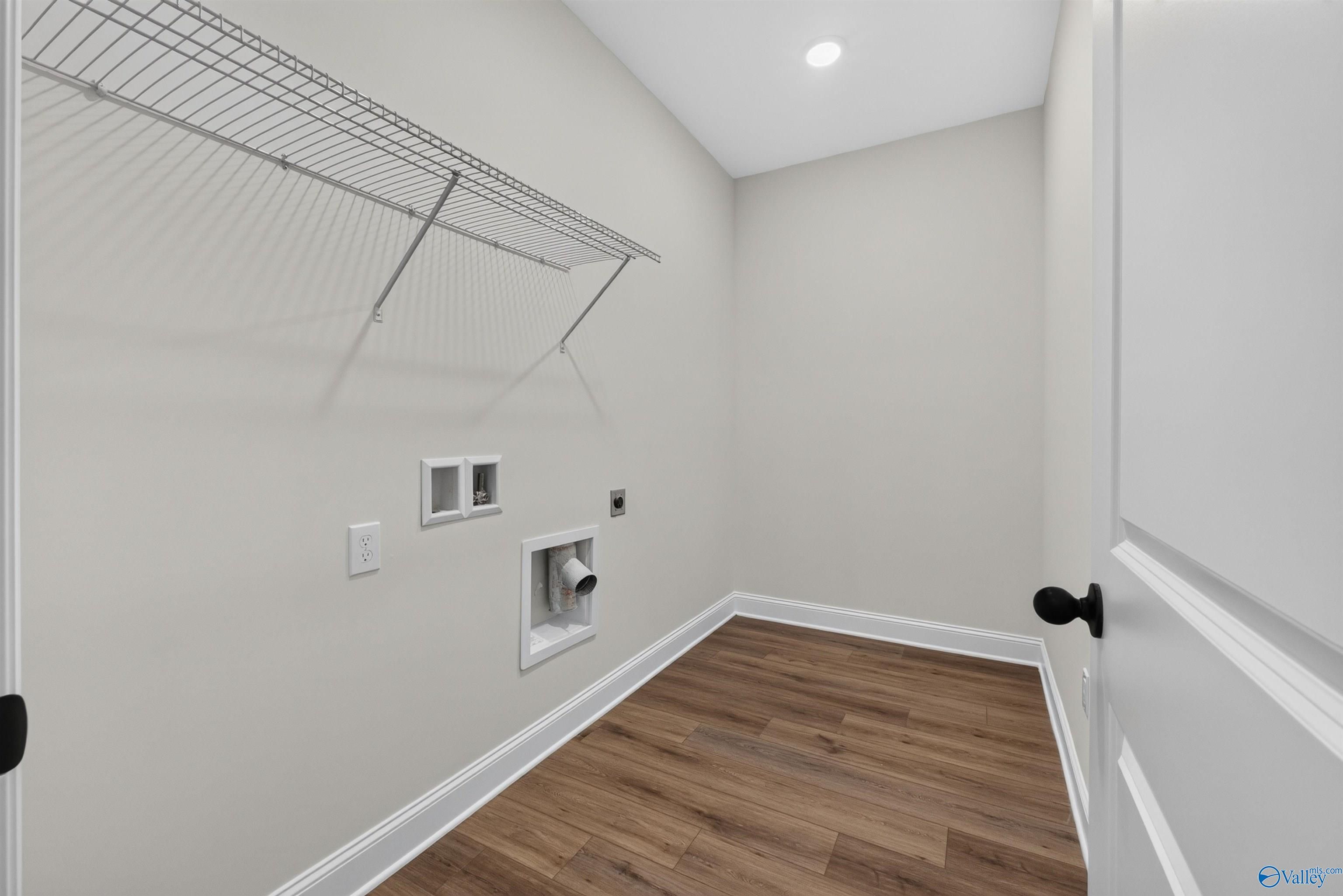 Laundry room with wire shelving, washer hookups, and wood-look flooring in Davidson Homes The Ashport L, Berry Cove, New Market, Alabama