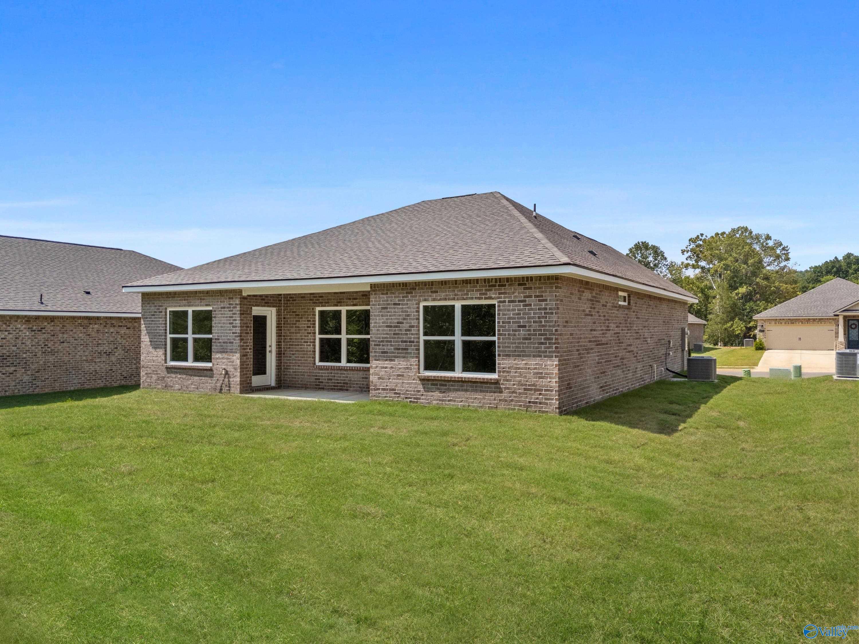 Single-story brick home with covered porch, large windows, lush green yard, and garage in Spragins Cove, Huntsville, Alabama - Davidson Homes The Asheville