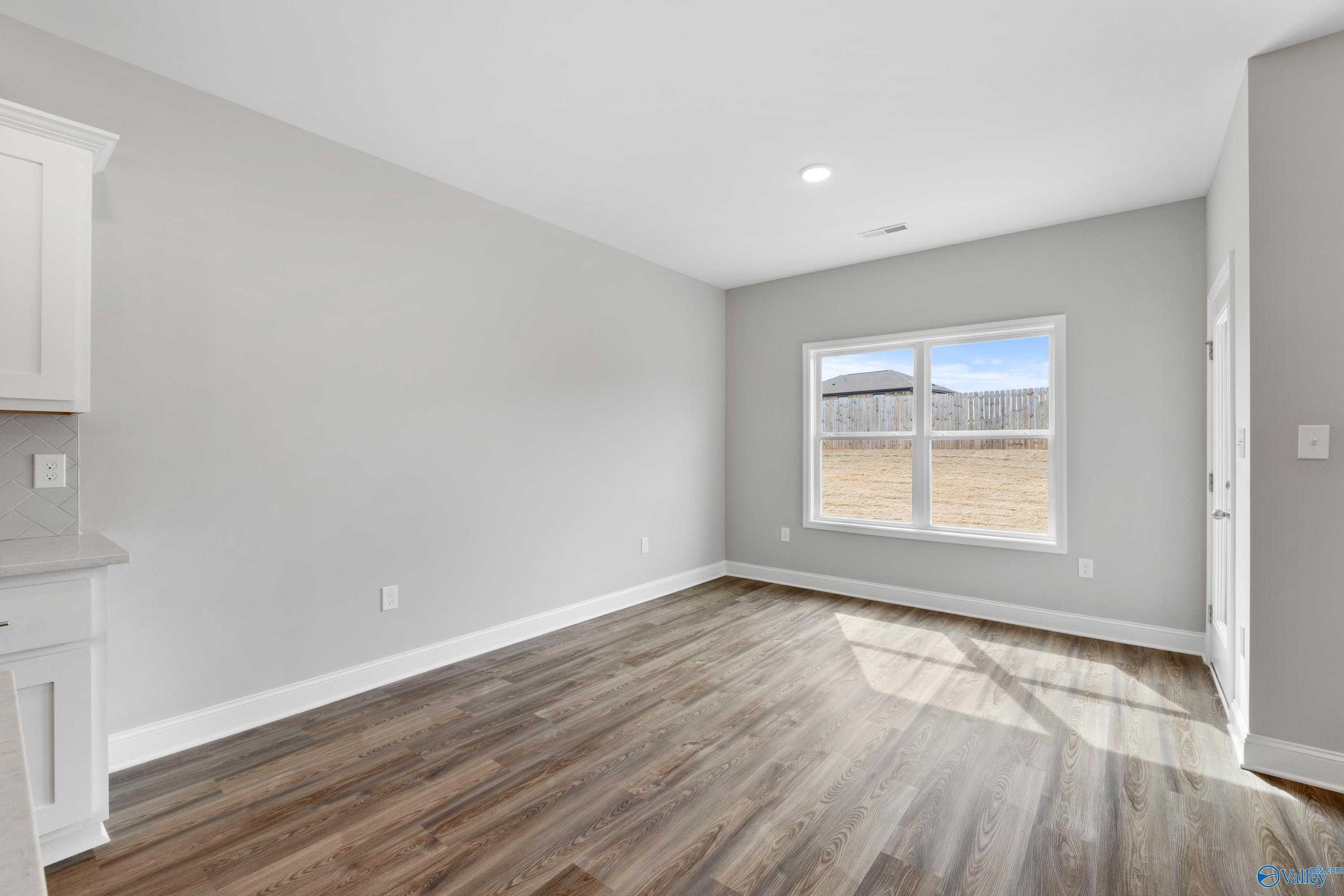 Bright secondary bedroom with gray walls, hardwood floors, large window to backyard in Davidson Homes The Aiken, Meridianville AL
