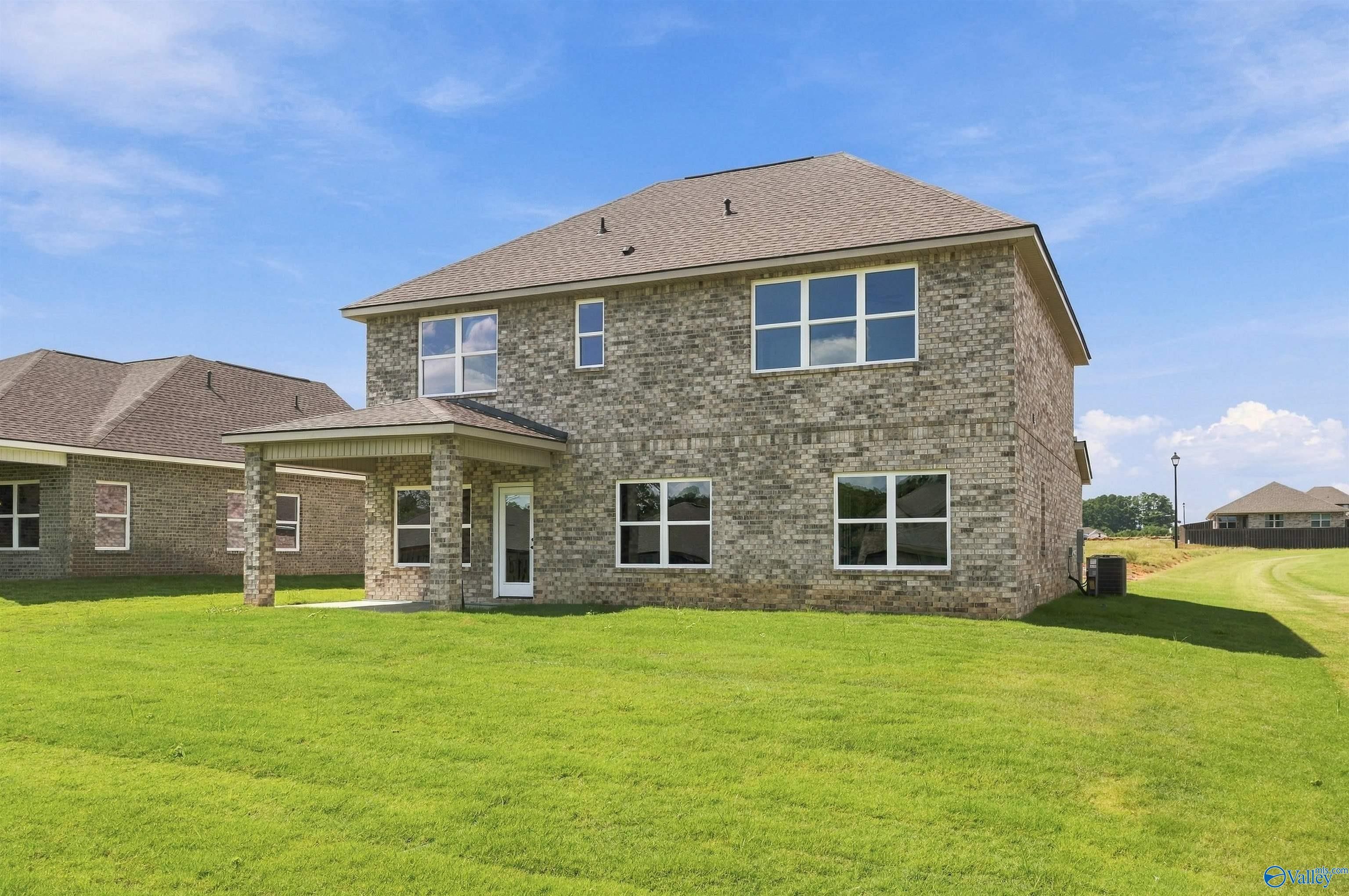 Rear exterior of 2-story brick home with covered patio and spacious backyard in The Meadows, Athens, Alabama by Davidson Homes