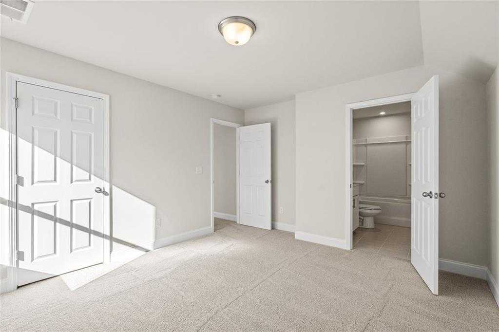 Bright secondary bedroom with attached bath and open doors in Davidson Homes The Ash C at Wehunt Meadows, Hoschton, Georgia