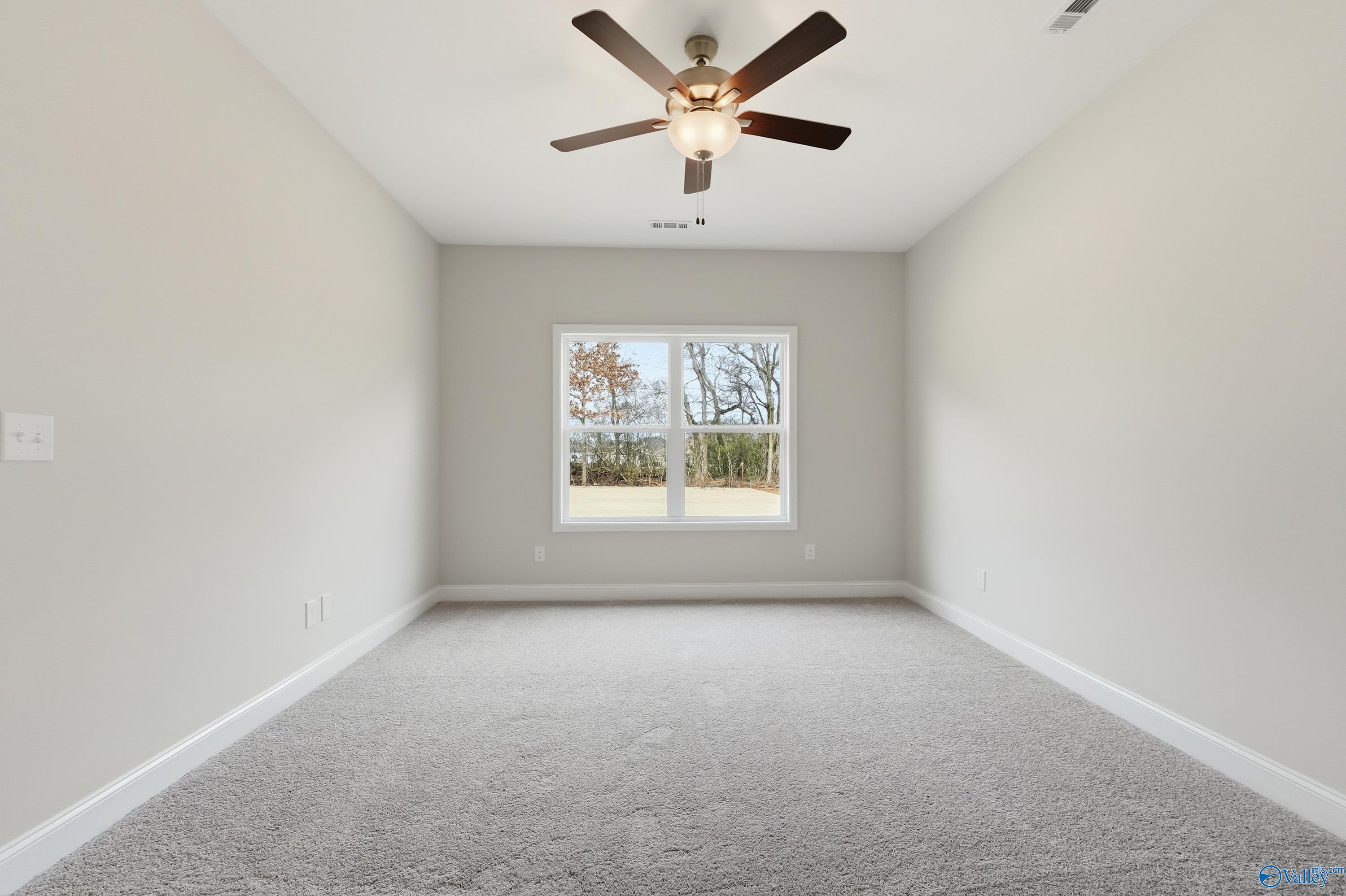 Spacious empty bedroom with ceiling fan and large windows overlooking trees in Davidson Homes The Franklin, Meridianville, Alabama