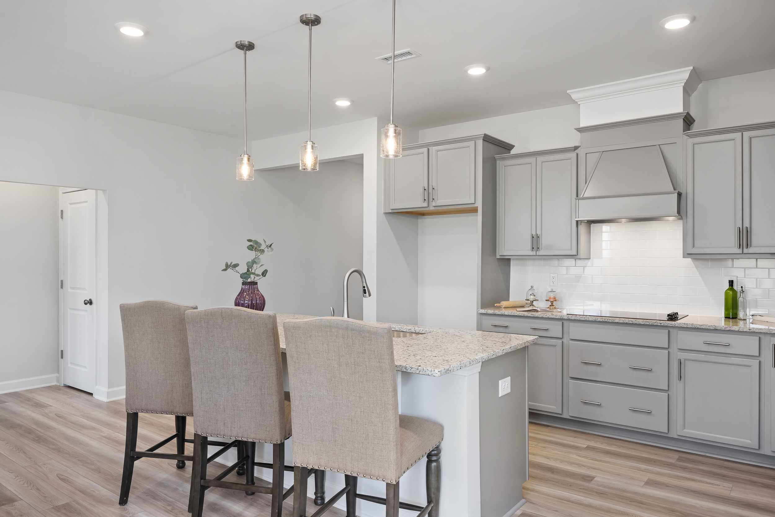 Spacious kitchen in The Daphne C featuring gray shaker cabinets, quartz island with bar stools, and pendant lights
