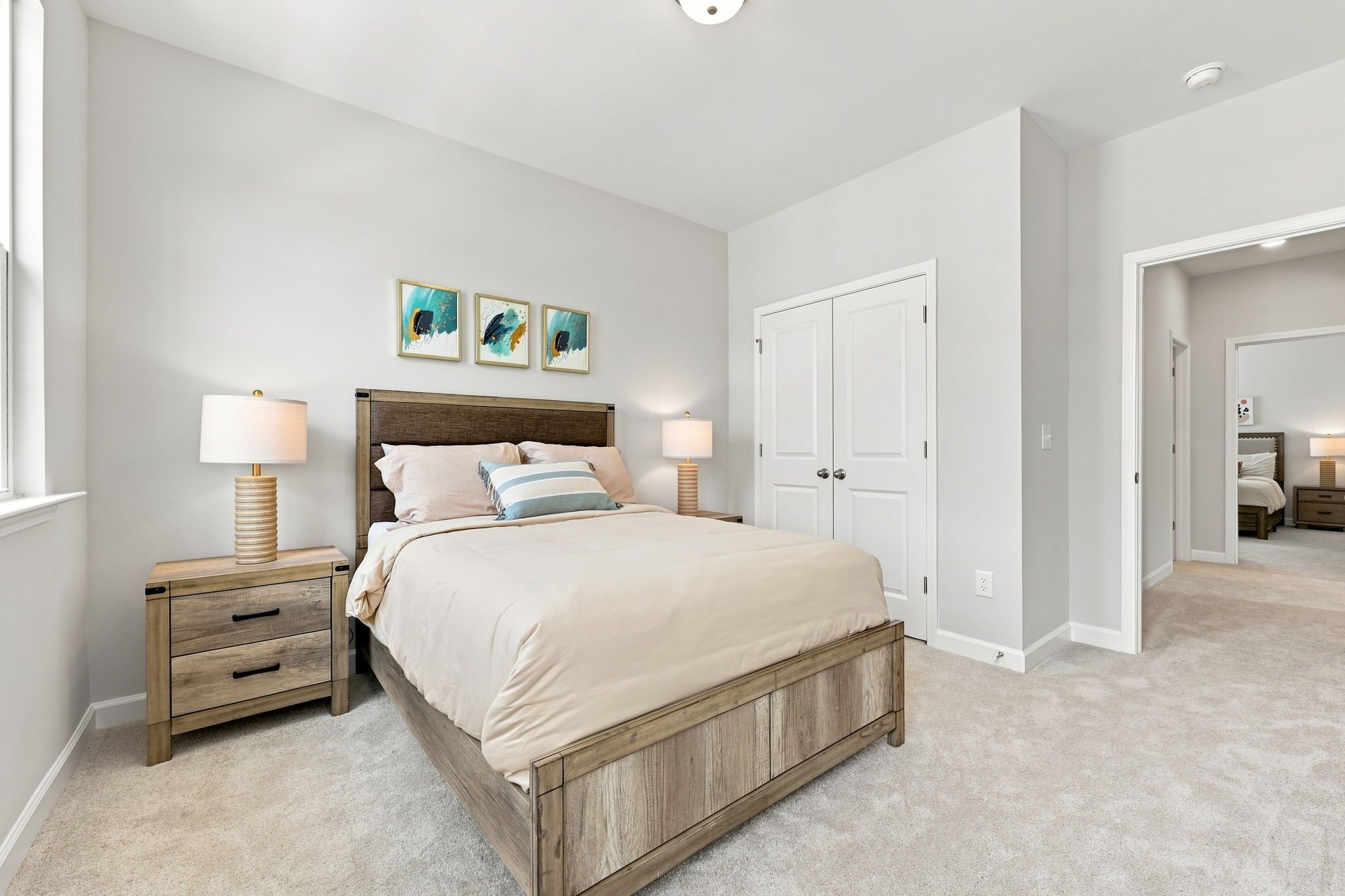 Spacious upper-floor bedroom in The Jordan A by Davidson Homes featuring a rustic wood bed frame and neutral decor.