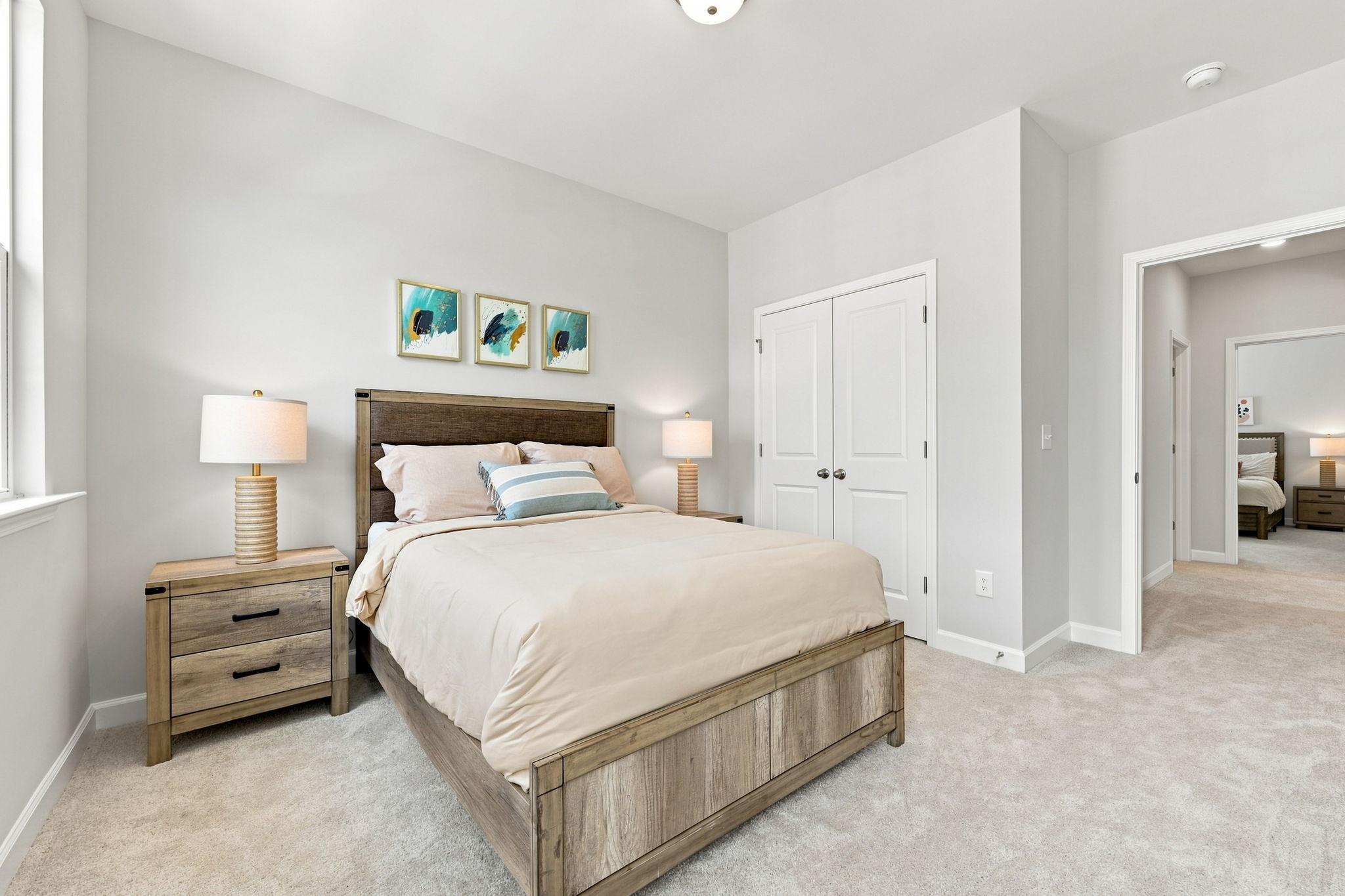 Spacious upper-floor bedroom in The Jordan A by Davidson Homes featuring a rustic wood bed frame and neutral decor.