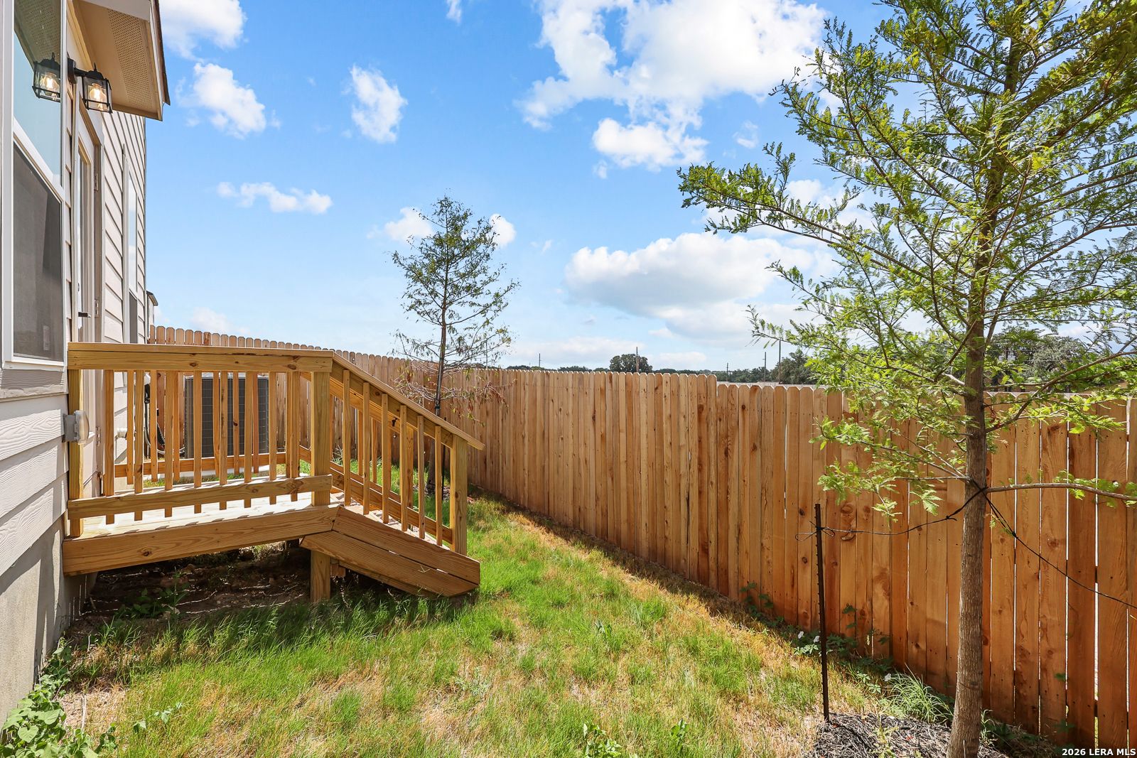 Private fenced backyard with wooden deck at The Gillian C home in Meadows at Oak Creek, San Antonio, Texas.
