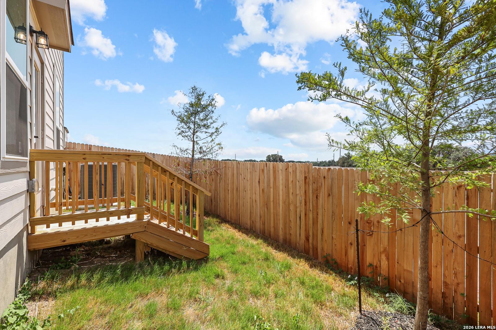 Private fenced backyard with wooden deck at The Gillian C home in Meadows at Oak Creek, San Antonio, Texas.