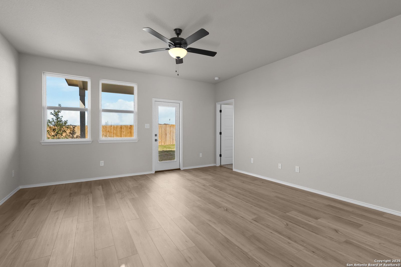 Spacious living room with ceiling fan, large windows, sliding doors to fenced backyard in 5-bedroom Davidson Homes The Brazos C, San Antonio