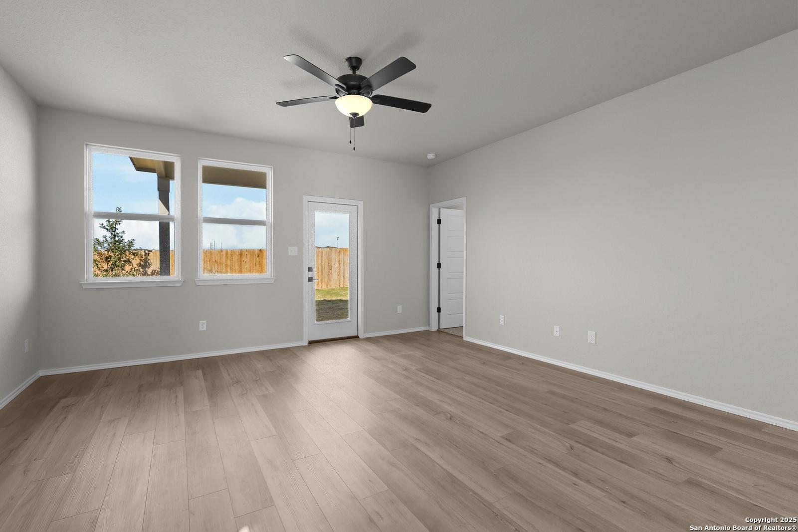Spacious living room with ceiling fan, large windows, sliding doors to fenced backyard in 5-bedroom Davidson Homes The Brazos C, San Antonio