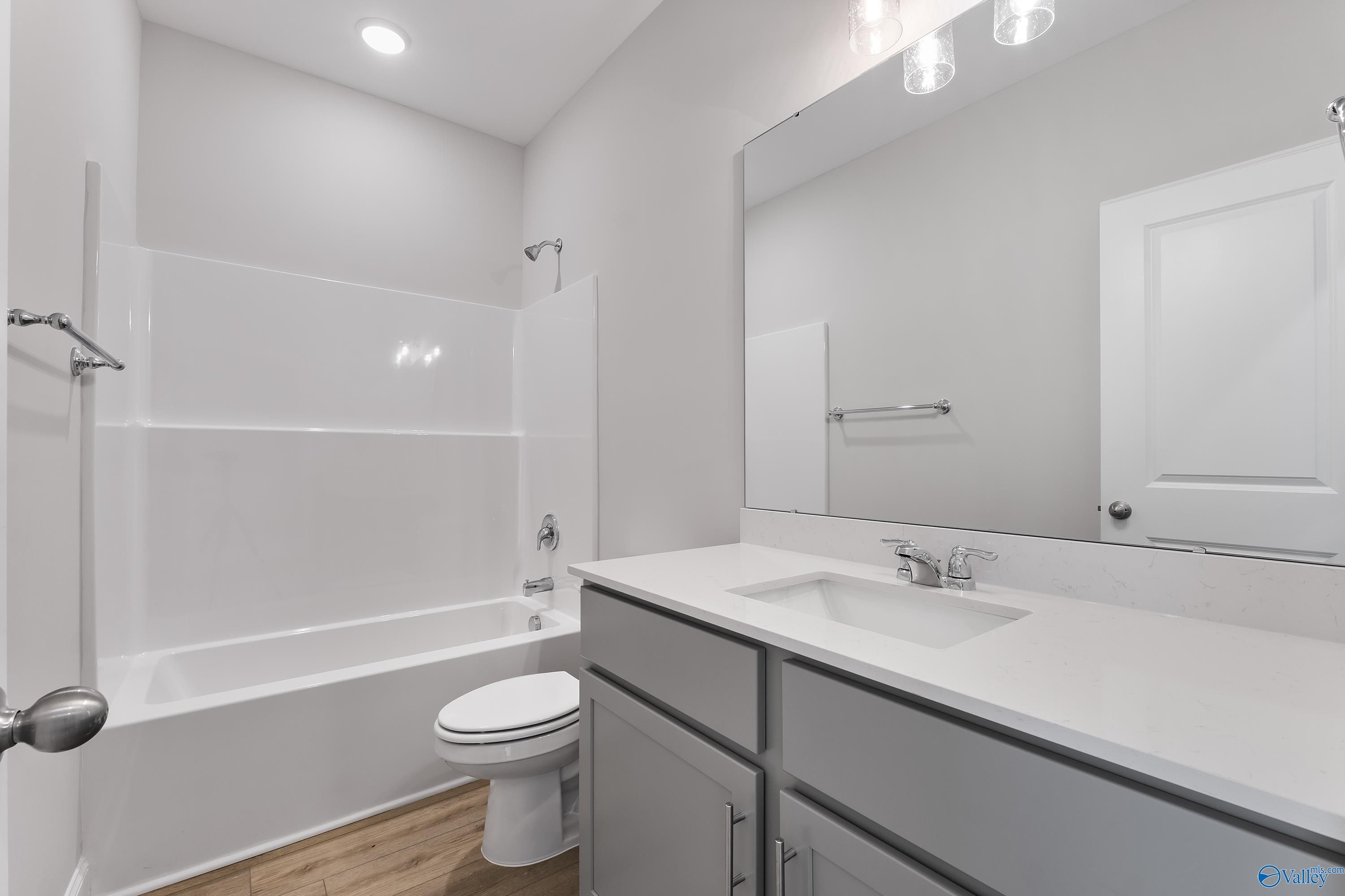 Modern full bathroom with white tub-shower combo, gray vanity, single sink, and toilet in The Daphne C floor plan by Davidson Homes, Huntsville, AL