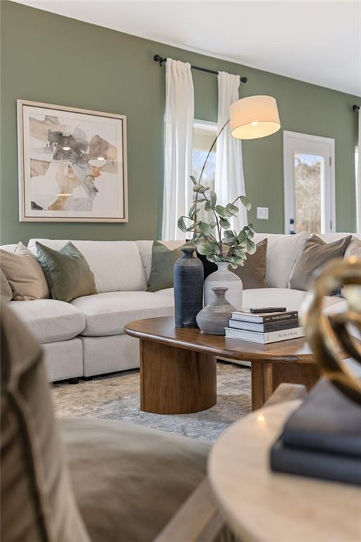 Modern living room with sage green walls and white sectional in The Rabun B floor plan at The Bluffs, Canton, Georgia.