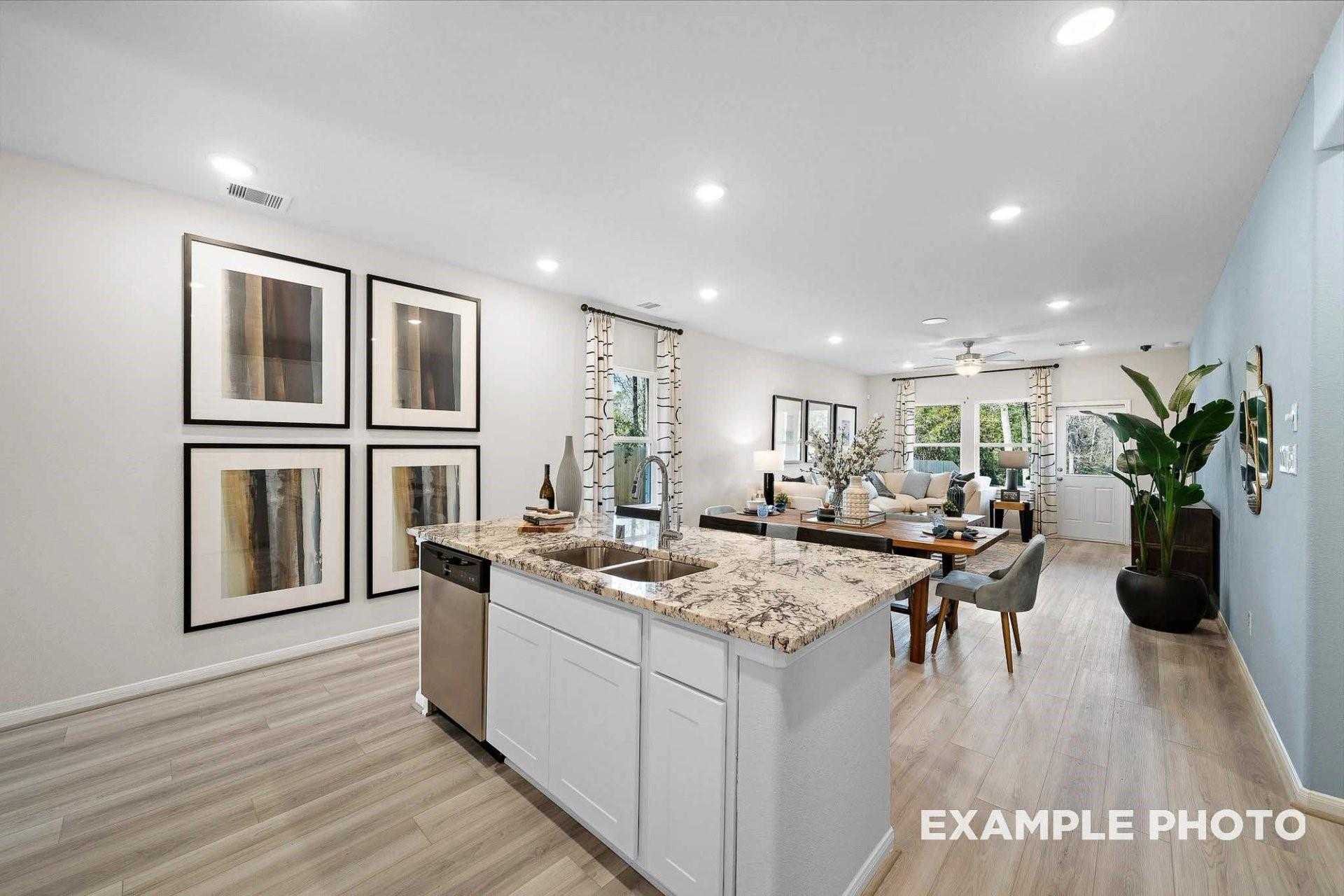 Open-concept kitchen with white cabinets, granite island sink, and adjacent dining area in Davidson Homes The San Marcos E, Magnolia Texas