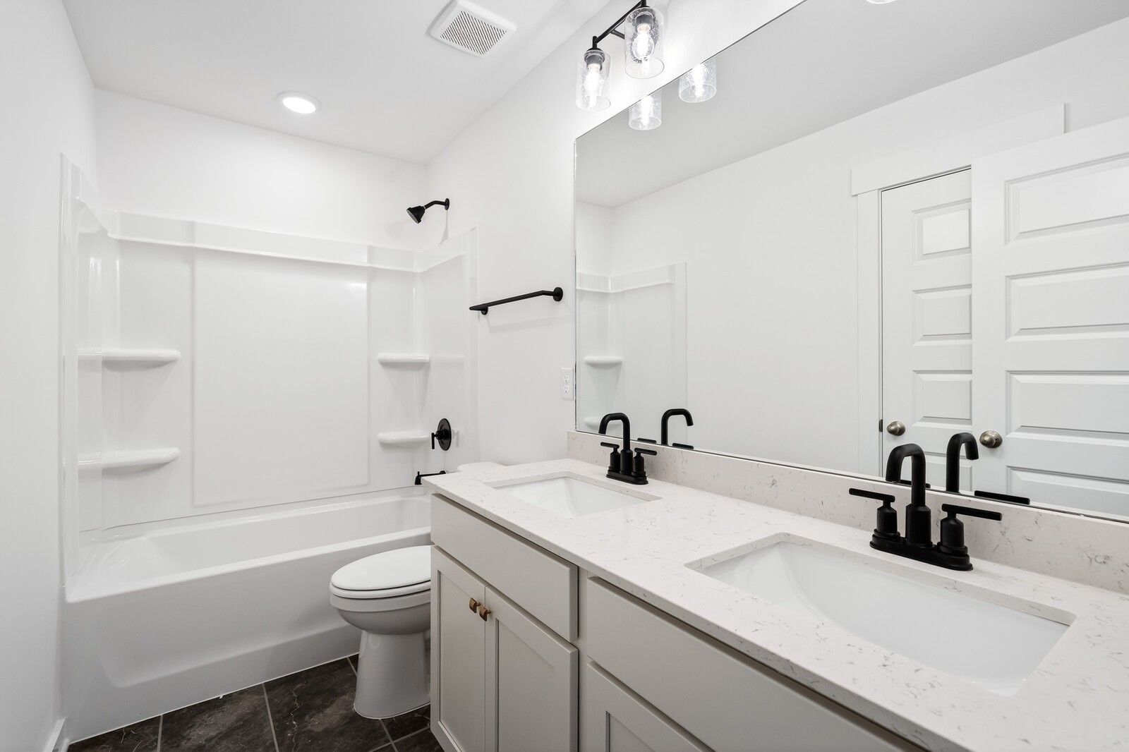 Modern bathroom with double vanity, quartz counters, black fixtures, tub, and glass shower in 5-bed Davidson Homes Ridgeport C, Gallatin, TN
