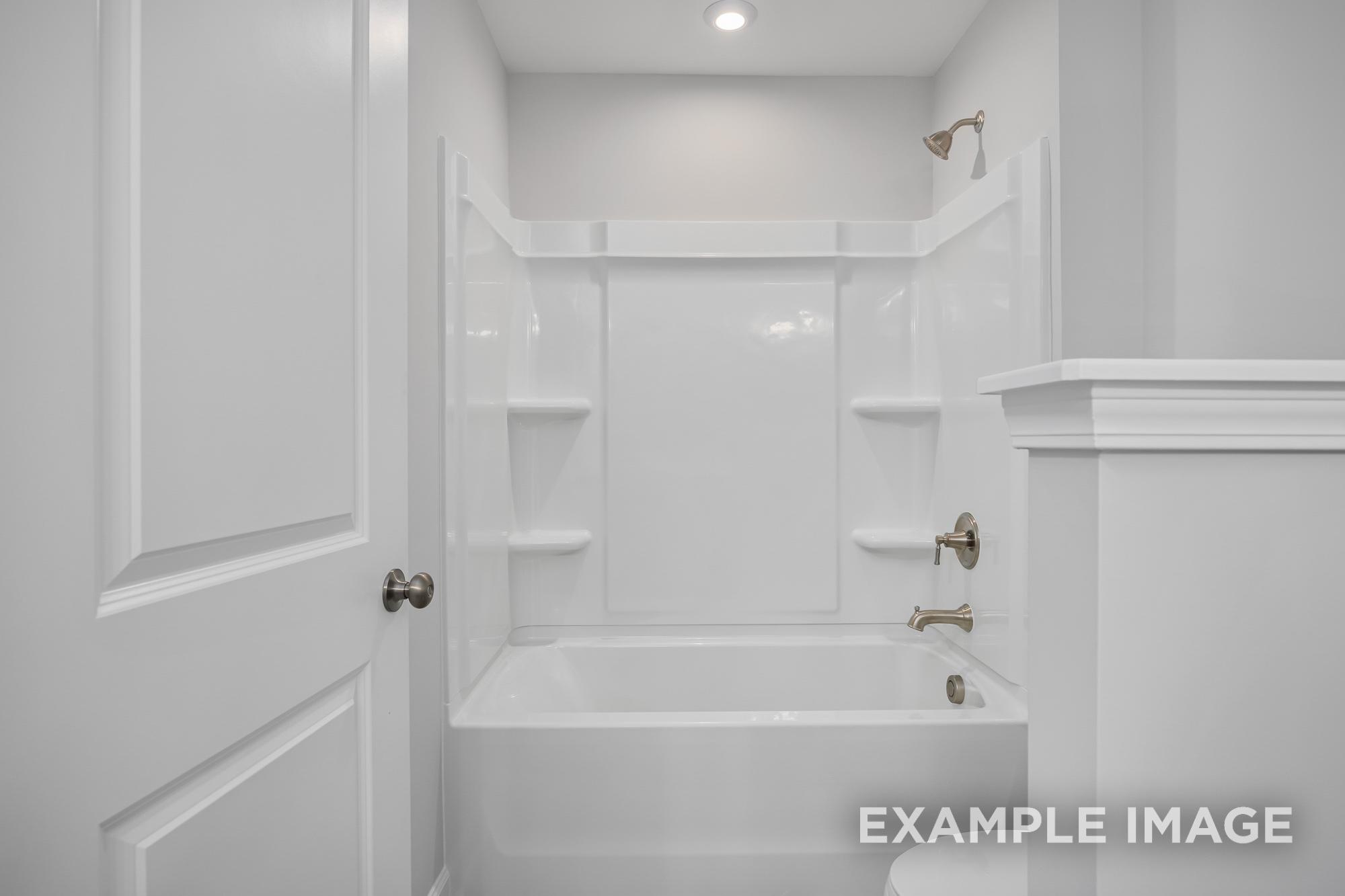 Spacious master bathroom in The Cypress B II featuring white tub-shower combo, built-in shelves, and modern fixtures